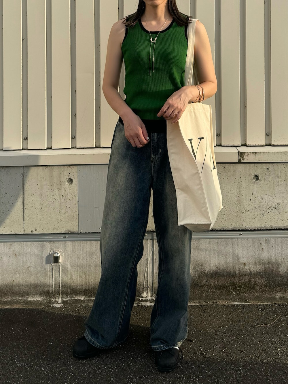 グリーン系のタンクトップ、ブラック系のスニーカー、ホワイト系のトートバッグを着用したレディースの夏コーディネートの3枚目の写真