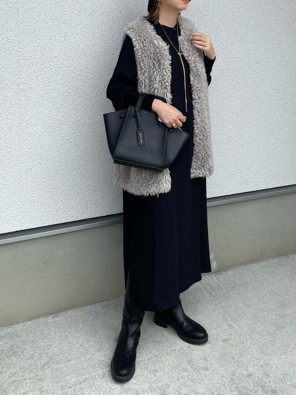 ブラック系のワンピース、ブラック系のハンドバッグ、ブラック系のブーツを着用したレディースの秋コーディネートの3枚目の写真