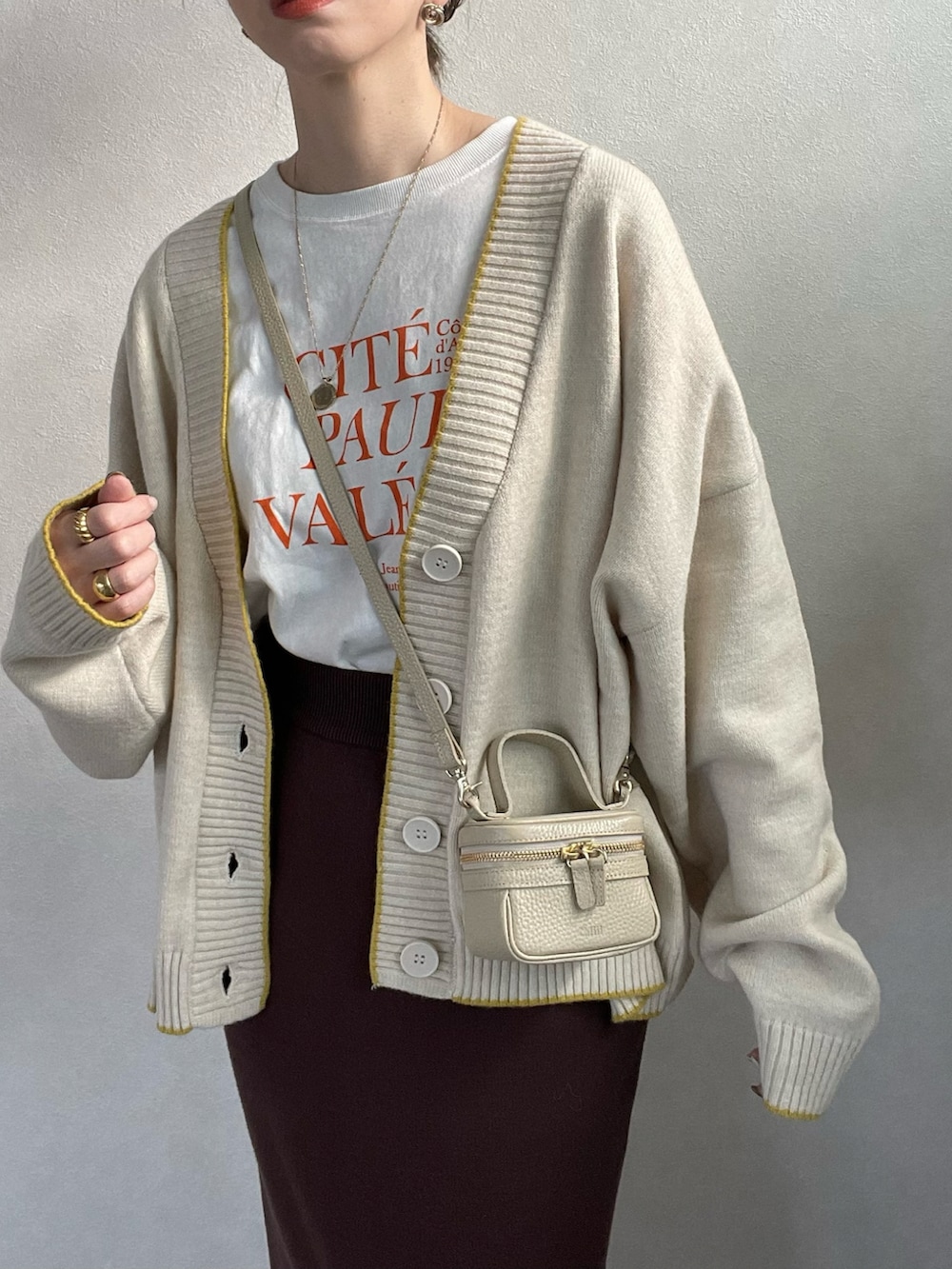 ホワイト系のカーディガン/ボレロ、ブラウン系のスカート、ブラウン系のブーツを着用したレディースの冬コーディネートの5枚目の写真