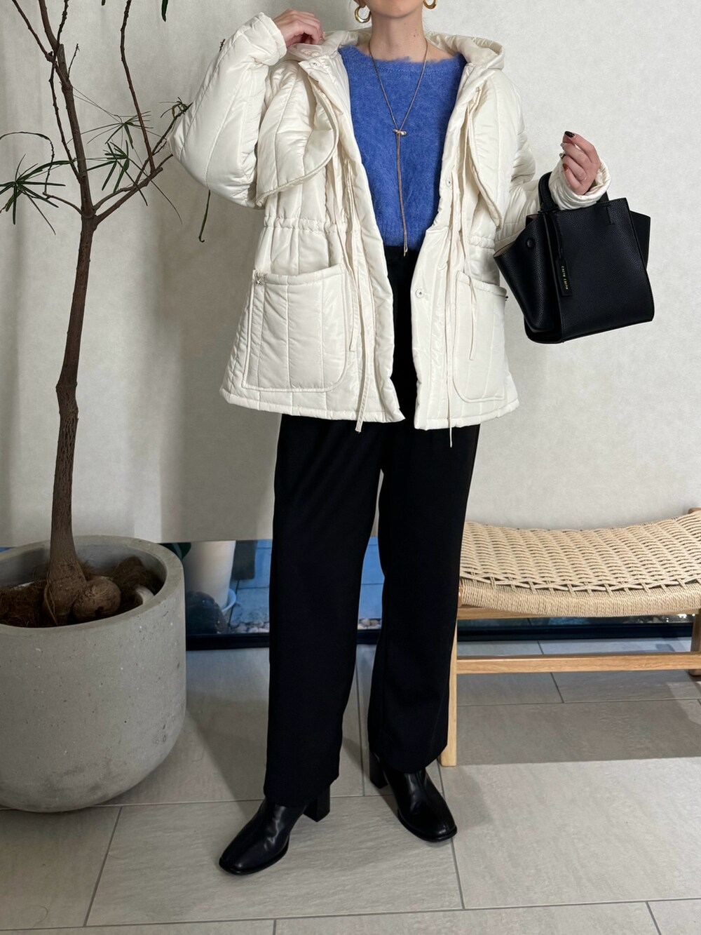 ブラック系のスラックス、ブルー系のニット/セーター、ブラック系のハンドバッグを着用したレディースの秋コーディネートの4枚目の写真