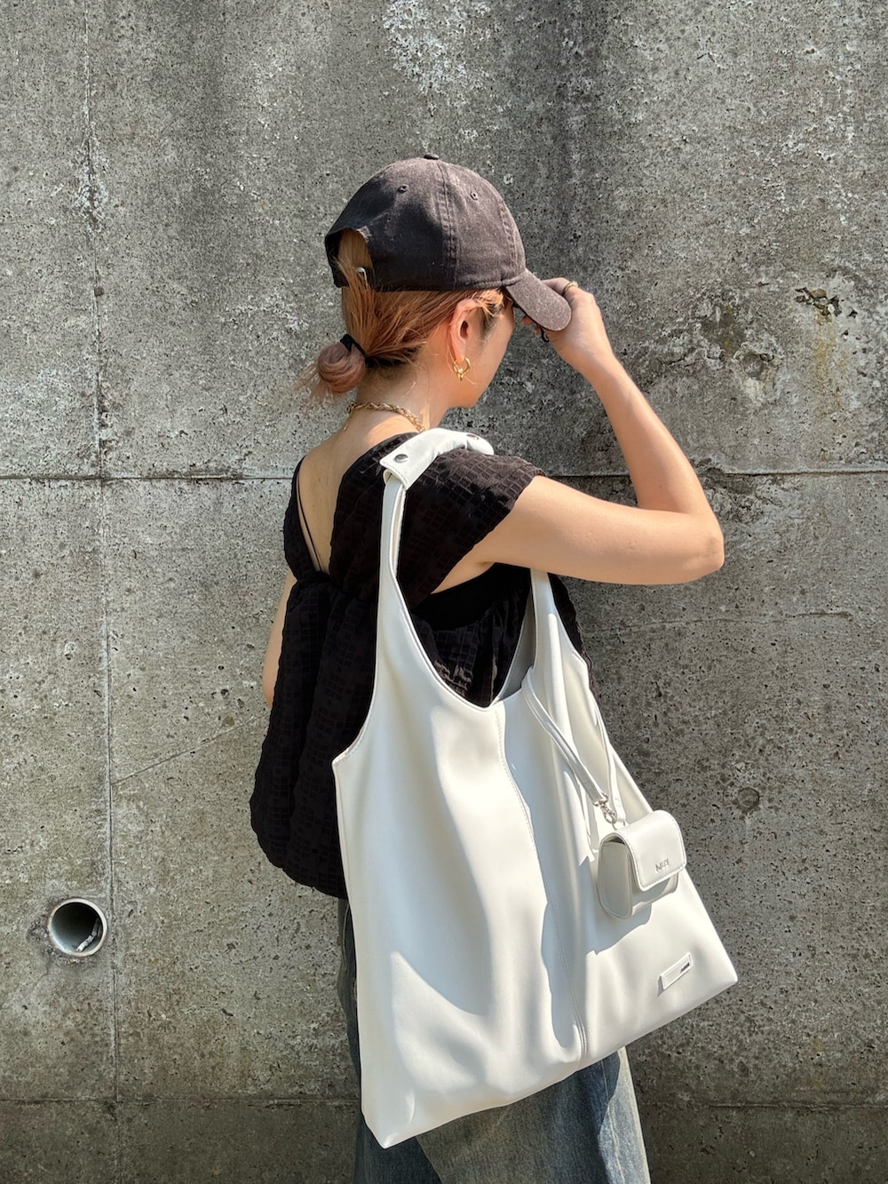 ホワイト系のトートバッグ、ブルー系のデニムパンツ、シルバー系のサンダルを着用したレディースの夏コーディネートの3枚目の写真