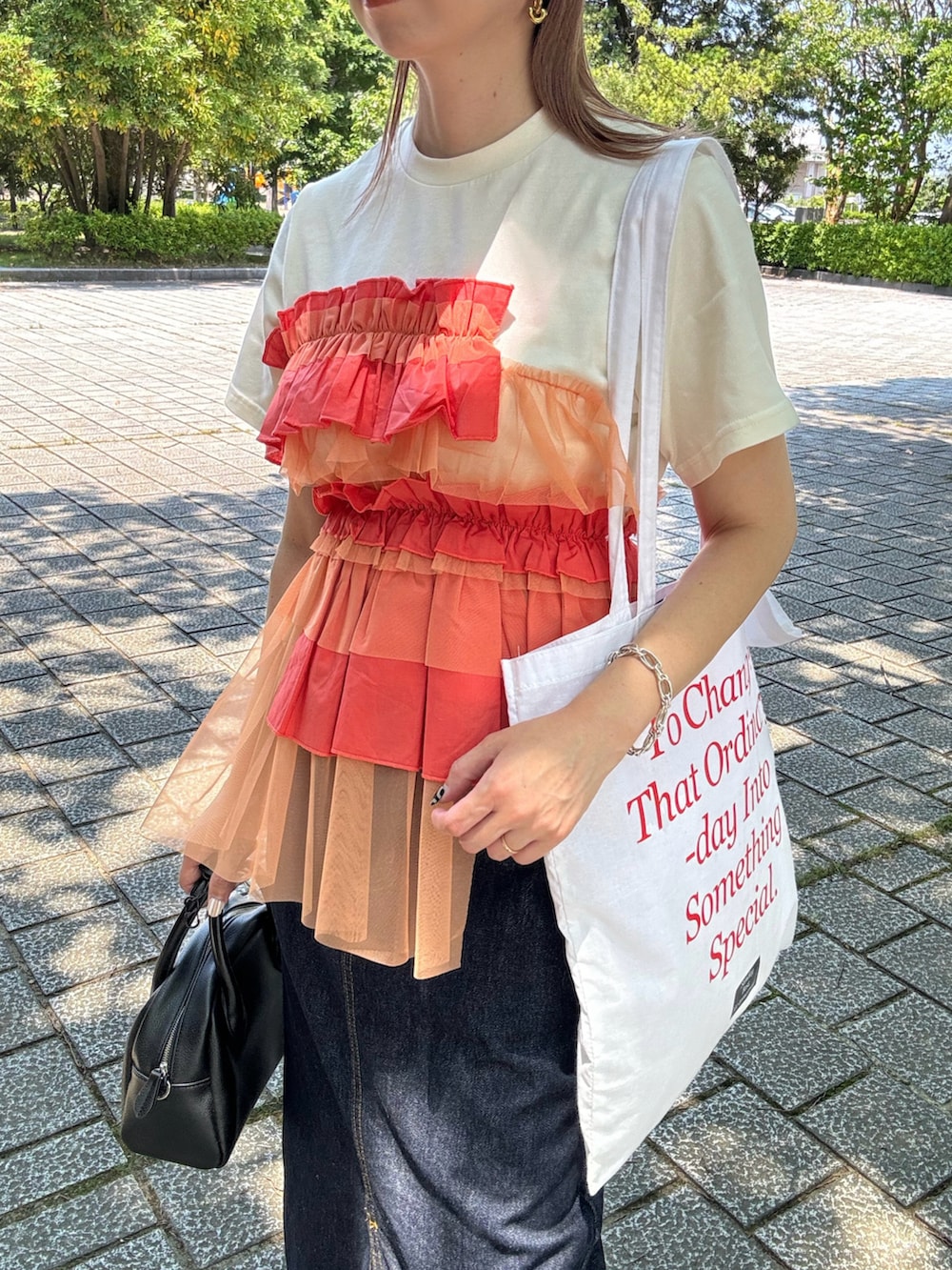 オレンジ系のTシャツ/カットソー、ブルー系のデニムスカート、ブラック系のスニーカーを着用したレディースの夏コーディネートの5枚目の写真
