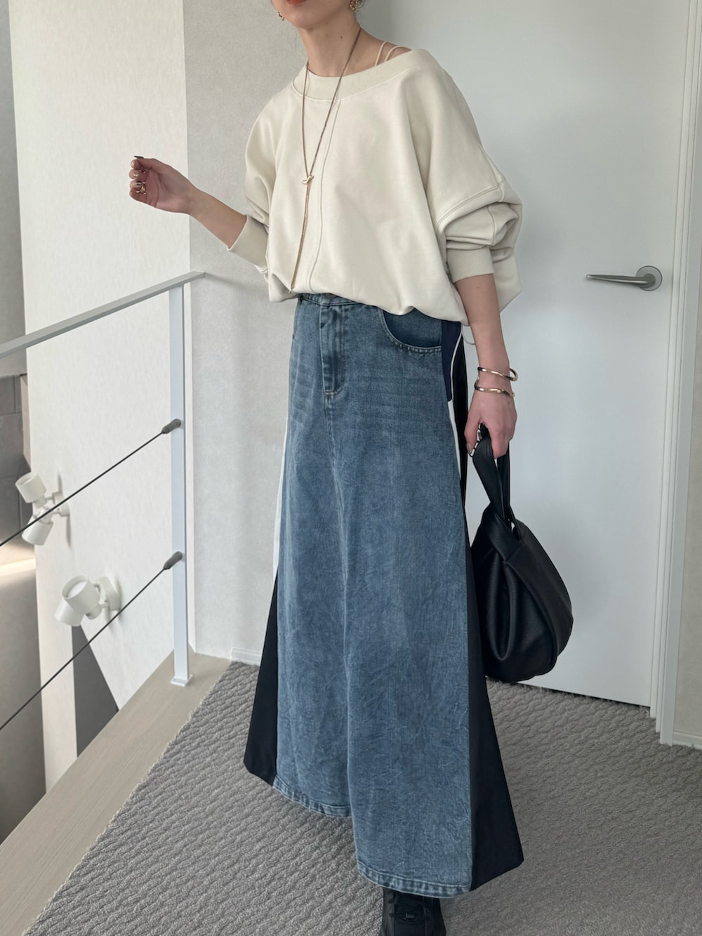 ホワイト系のスウェット、ブルー系のスカート、ブラック系のスニーカーを着用したレディースの春コーディネートの2枚目の写真