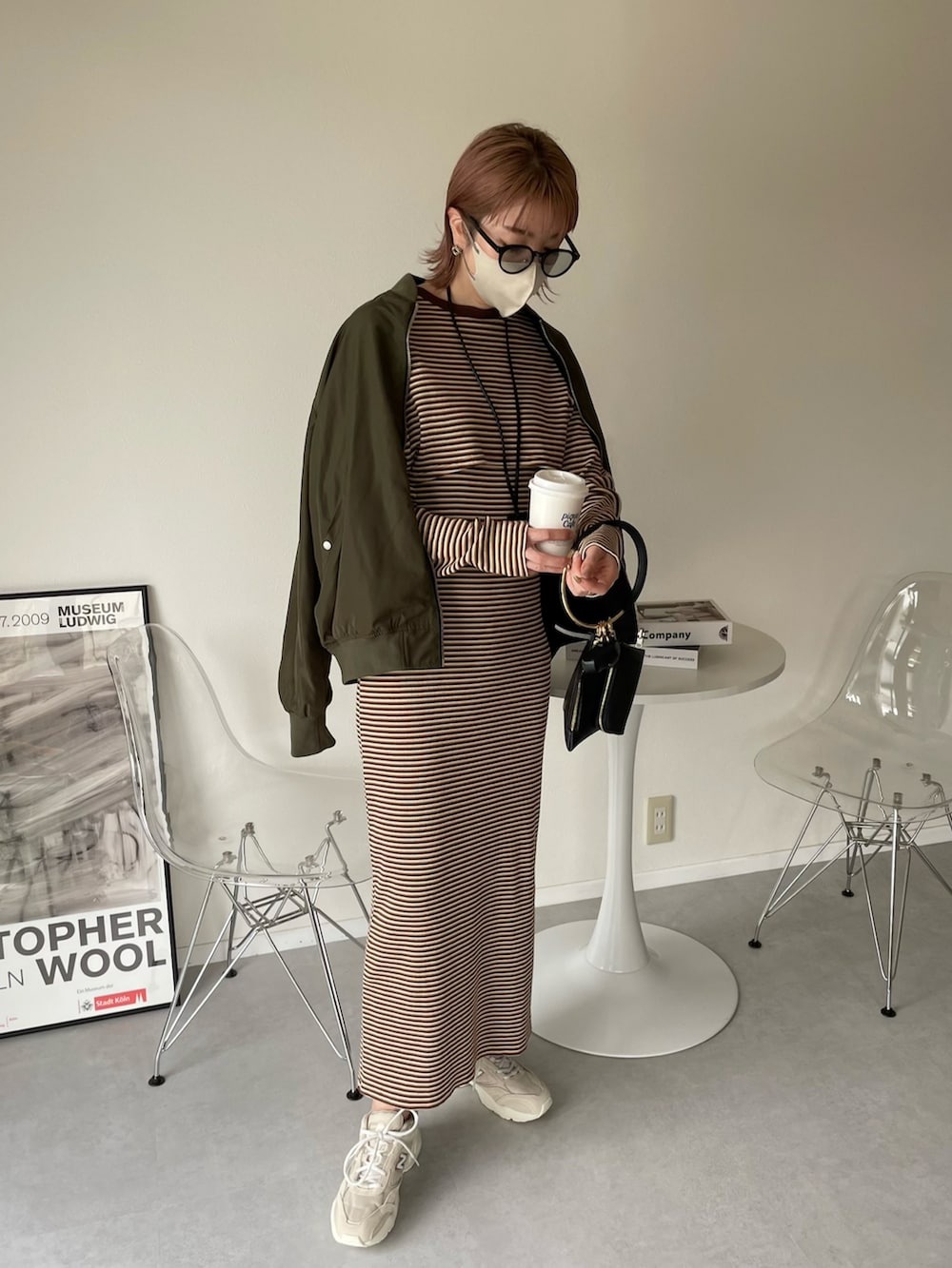 ブラウン系のワンピース、ブラック系のハンドバッグ、グリーン系のMA-1を着用したレディースの春コーディネートの2枚目の写真