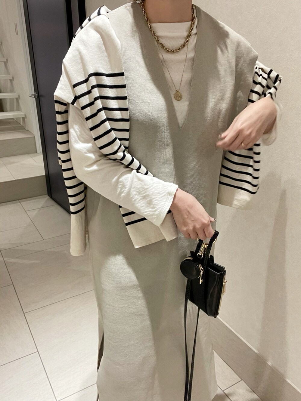 ベージュ系のワンピース、ブラック系のショルダーバッグ、ブラック系のブーツを着用したレディースの冬コーディネートの2枚目の写真