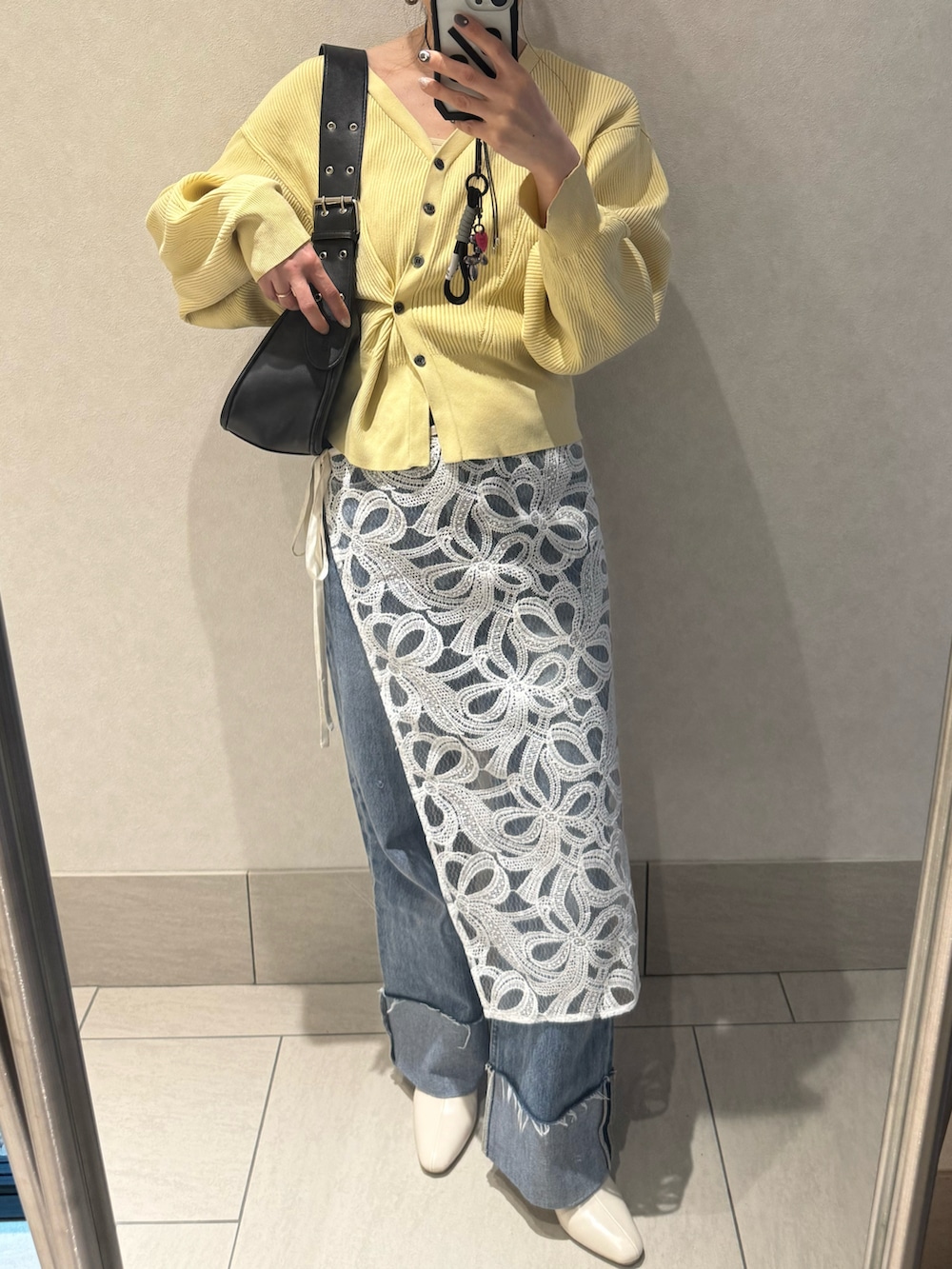 イエロー系のカーディガン/ボレロ、ホワイト系のスカート、ブラック系のハンドバッグを着用したレディースの春コーディネートの2枚目の写真