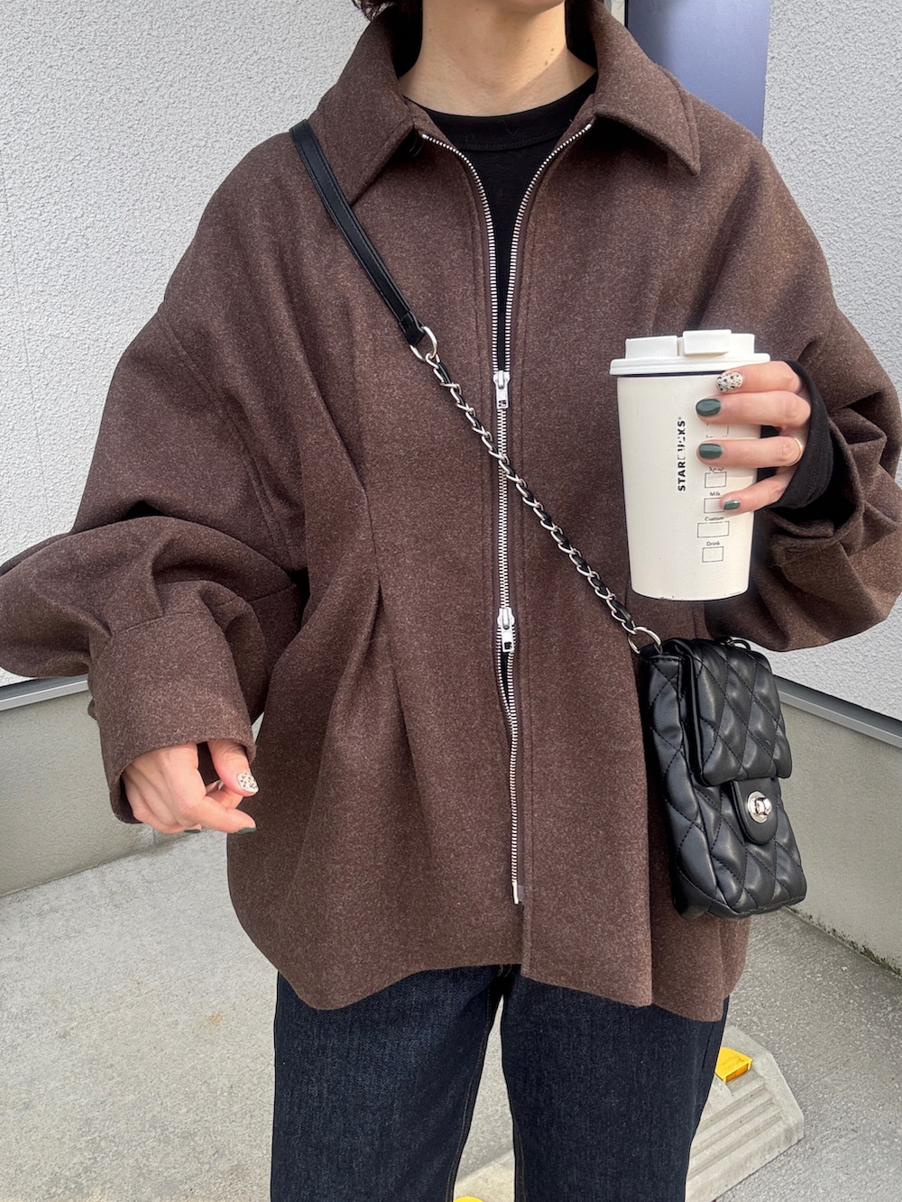 ブラウン系のブルゾン、ブルー系のデニムパンツ、ブラック系のショルダーバッグを着用したレディースの秋コーディネートの4枚目の写真