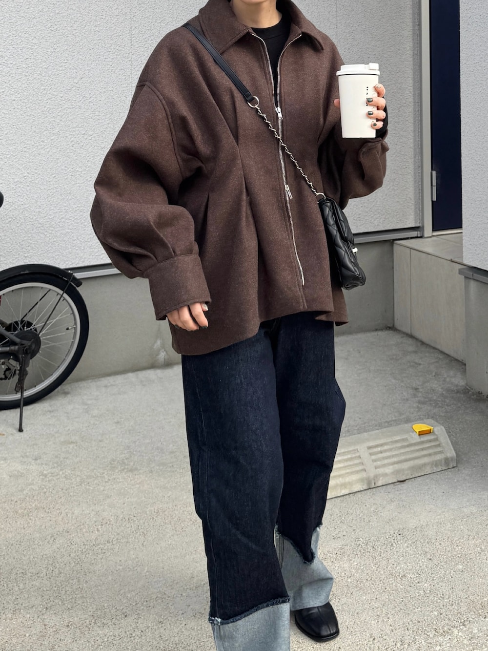 ブラウン系のブルゾン、ブルー系のデニムパンツ、ブラック系のショルダーバッグを着用したレディースの秋コーディネートの3枚目の写真