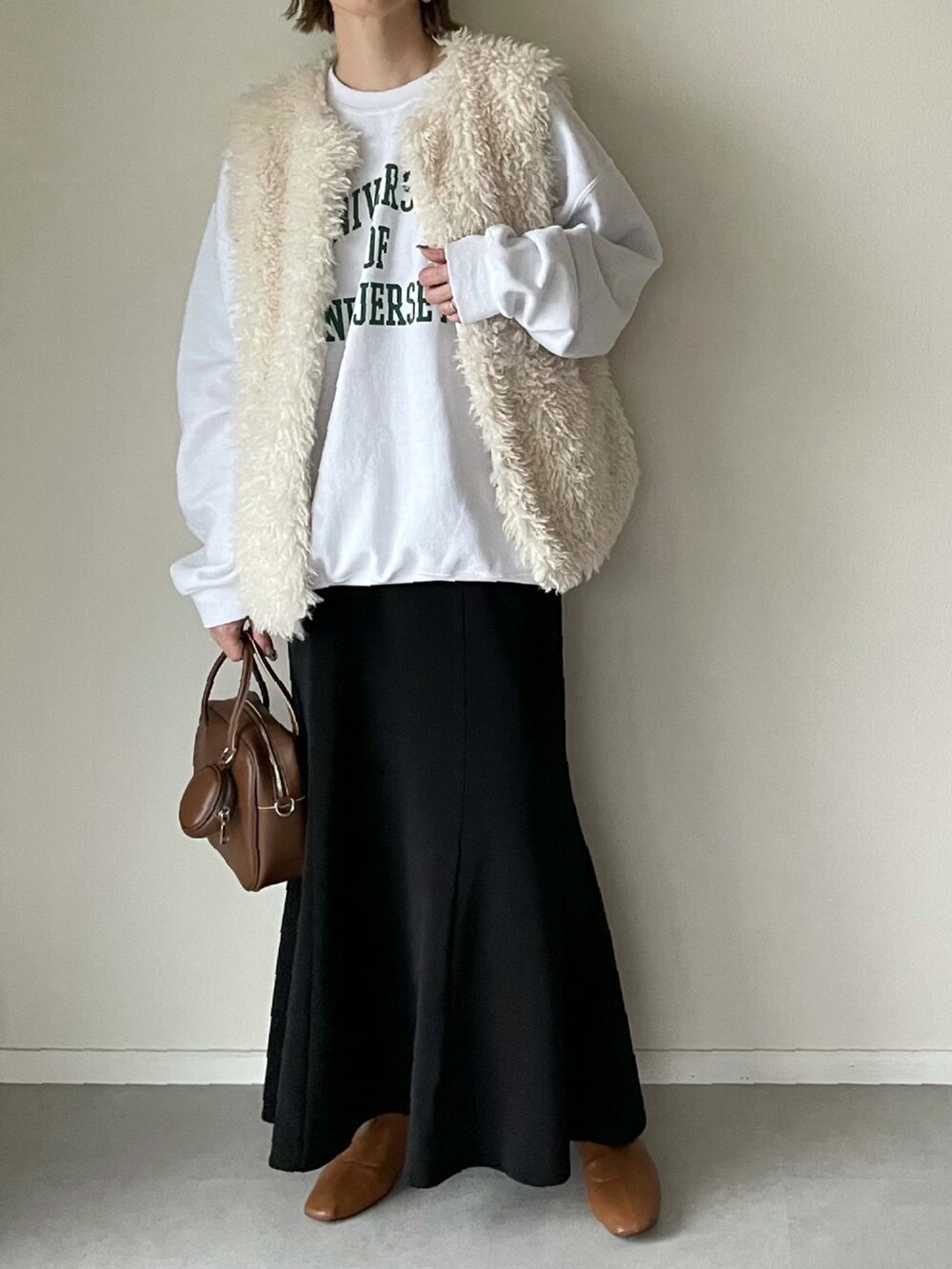 ホワイト系のベスト、ブラック系のスカート、ホワイト系のスウェットを着用したレディースの冬コーディネートの2枚目の写真
