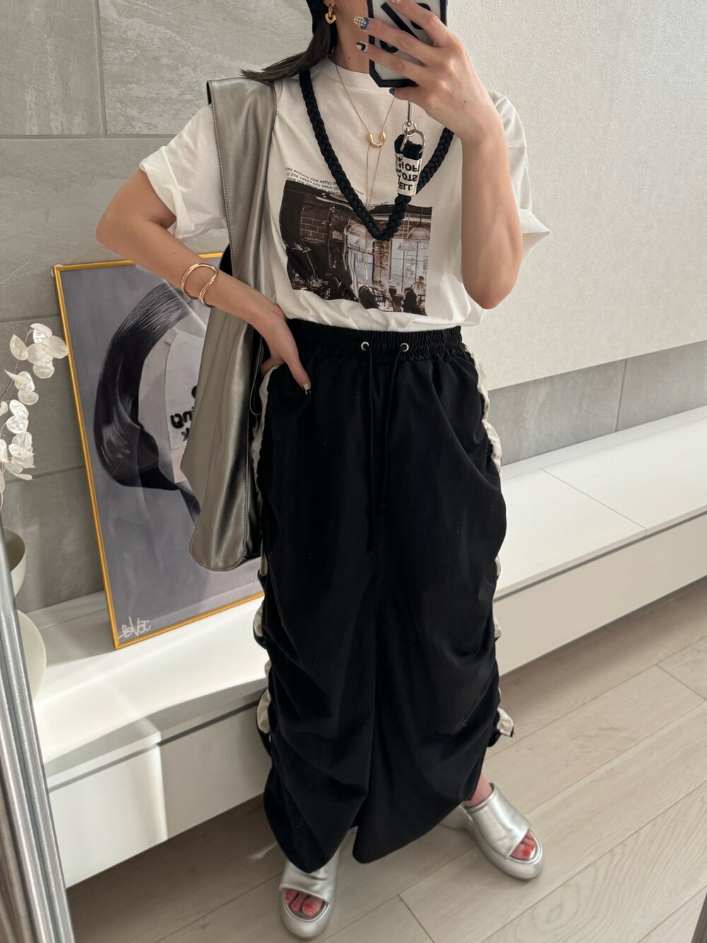 ブラック系のスカート、ホワイト系のTシャツ/カットソー、シルバー系のサンダルを着用したレディースの夏コーディネートの4枚目の写真