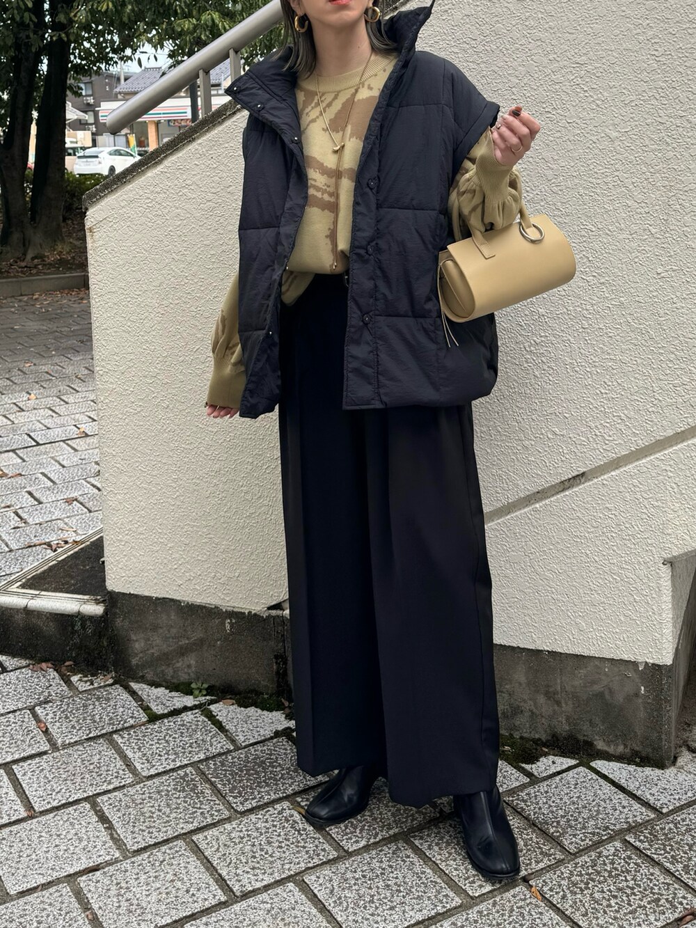 グリーン系のニット/セーター、ブラック系のその他パンツ、ベージュ系のハンドバッグを着用したレディースの秋コーディネートの5枚目の写真