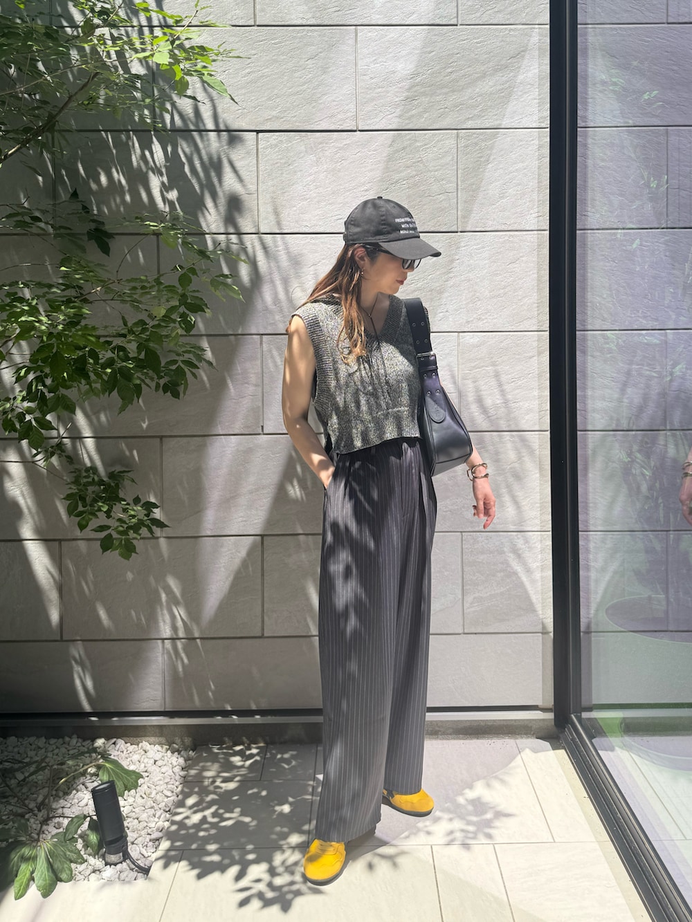 ブラック系のベスト、グレー系のスラックス、ブラック系のハンドバッグを着用したレディースの夏コーディネートの3枚目の写真