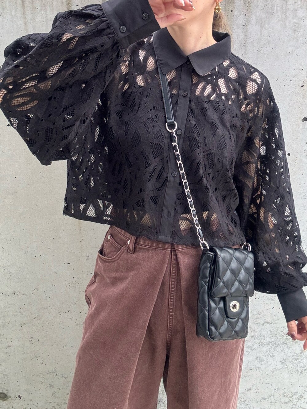 ブラウン系のデニムパンツ、ブラック系のショルダーバッグ、ブラック系のシャツ/ブラウスを着用したレディースの秋コーディネートの5枚目の写真