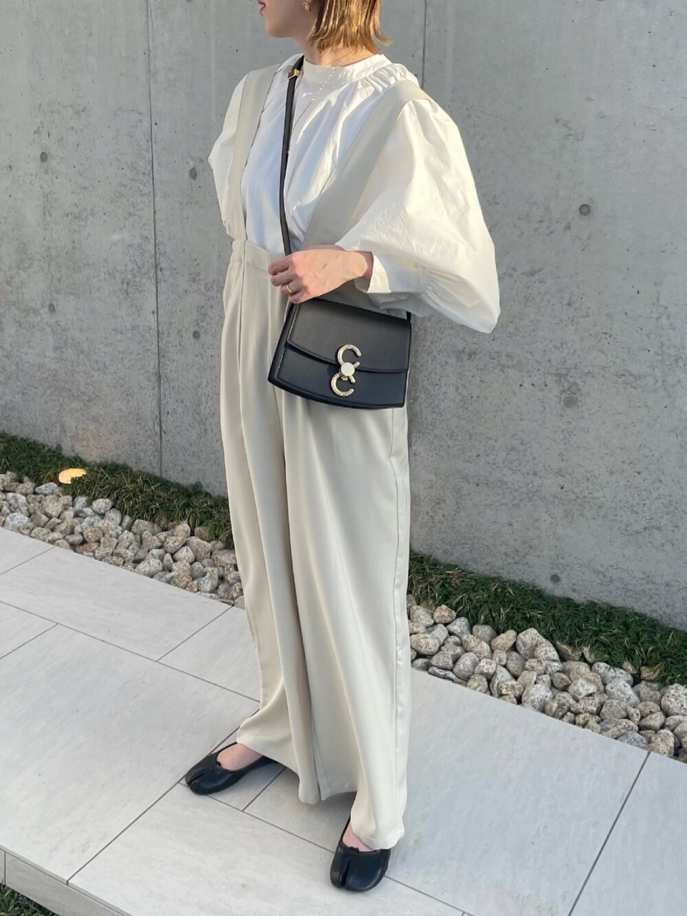 ホワイト系のサロペット/オーバーオール、ホワイト系のシャツ/ブラウス、ブラック系のパンプスを着用したレディースの春コーディネートの3枚目の写真