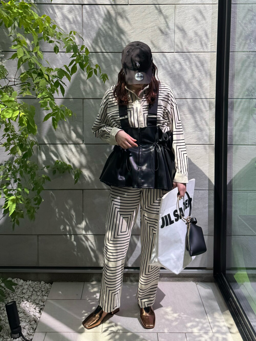 ブラック系のベスト、ゴールド系のパンプス、ホワイト系のシャツ/ブラウスを着用したレディースの春コーディネートの2枚目の写真
