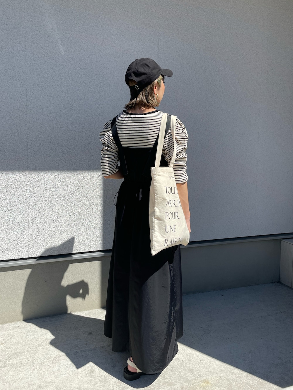 ブラック系のワンピース、ホワイト系のサンダルを着用したレディースの夏コーディネートの2枚目の写真