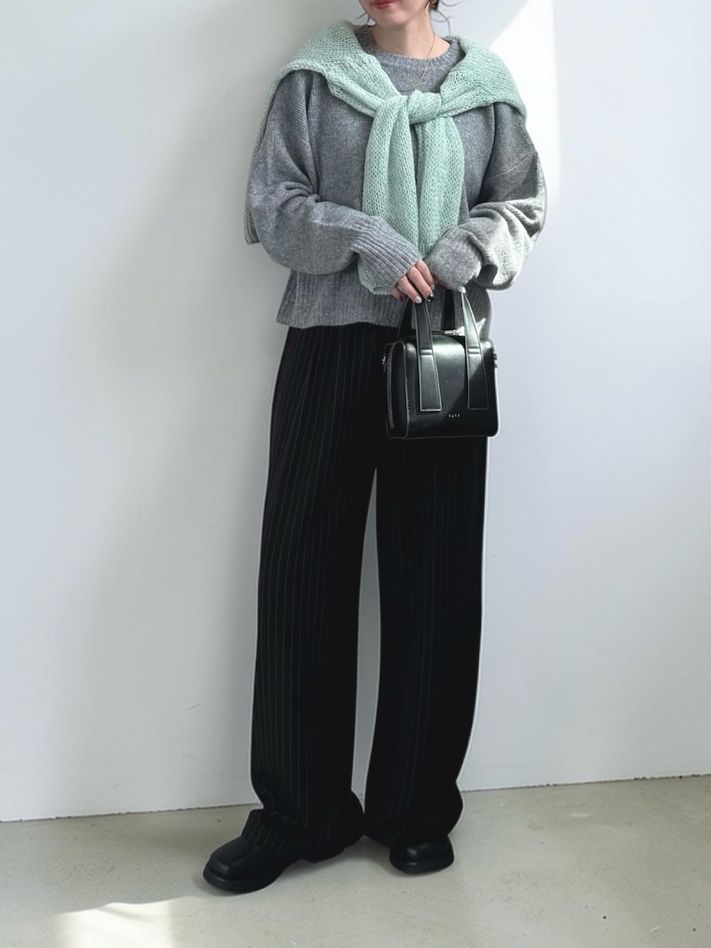 ブラック系のスラックス、ブラック系のその他シューズ、グリーン系のニット/セーターを着用したレディースの春コーディネートの3枚目の写真