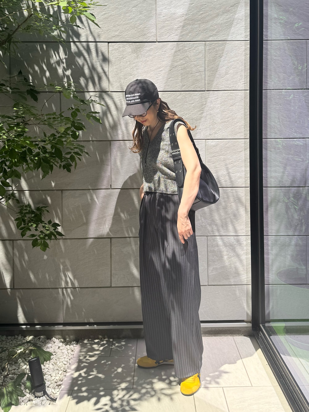 ブラック系のベスト、グレー系のスラックス、ブラック系のハンドバッグを着用したレディースの夏コーディネートの2枚目の写真