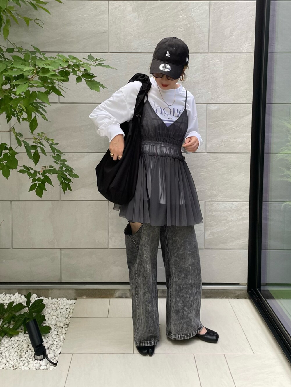 グレー系のキャミソール、ホワイト系のスウェット、ブラック系のデニムパンツを着用したレディースの秋コーディネートの2枚目の写真