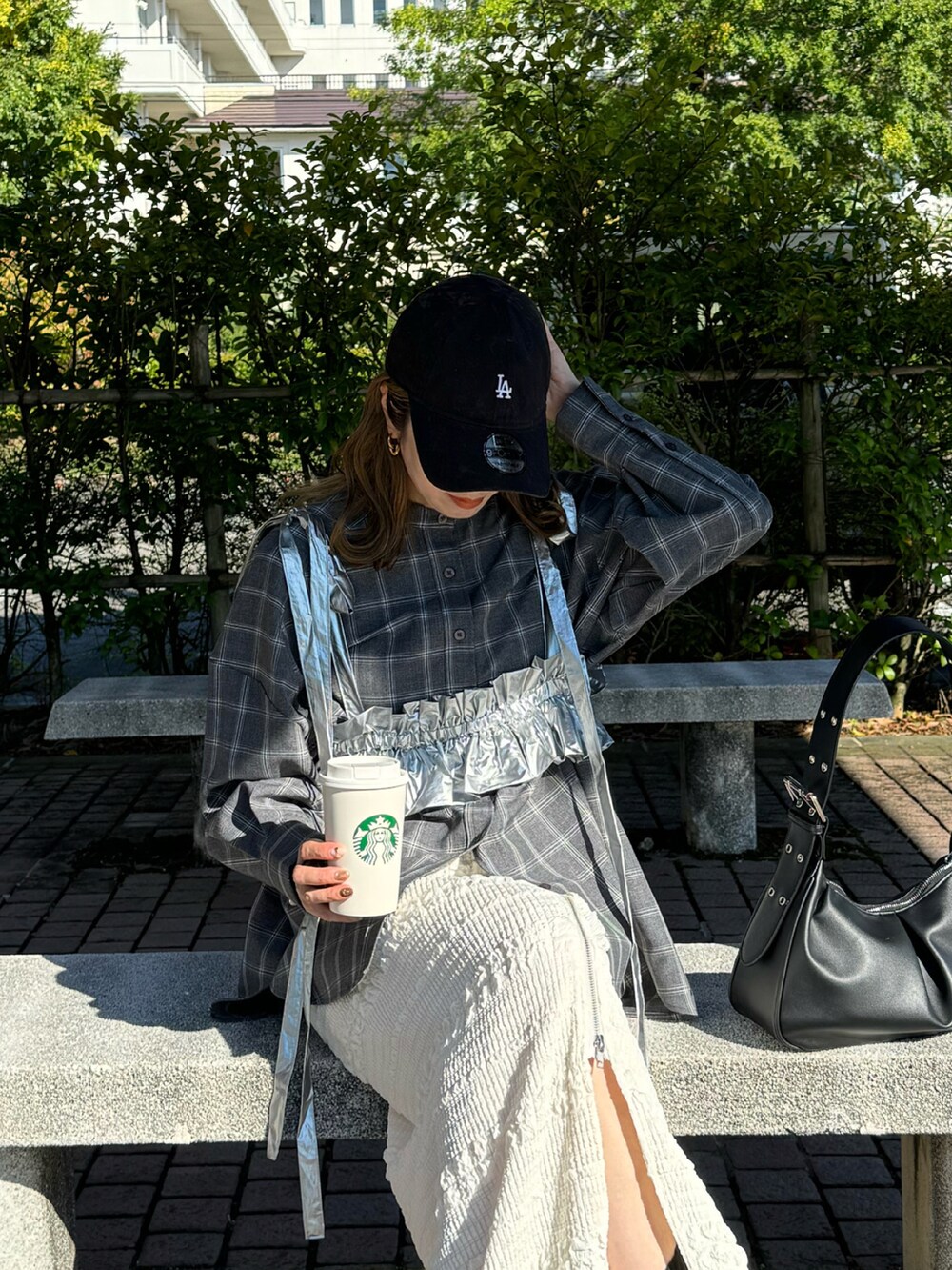 ホワイト系のスカート、ブラック系のスニーカー、ブラック系のハンドバッグを着用したレディースの秋コーディネートの2枚目の写真