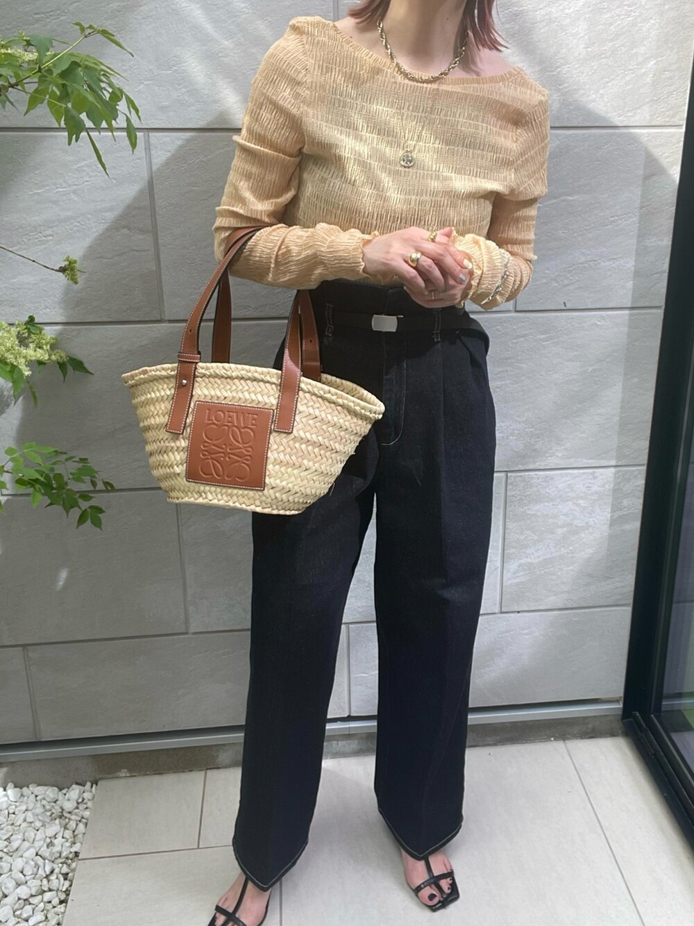 オレンジ系のTシャツ/カットソー、ブラック系のデニムパンツ、ブラック系のサンダルを着用したレディースの春コーディネートの3枚目の写真