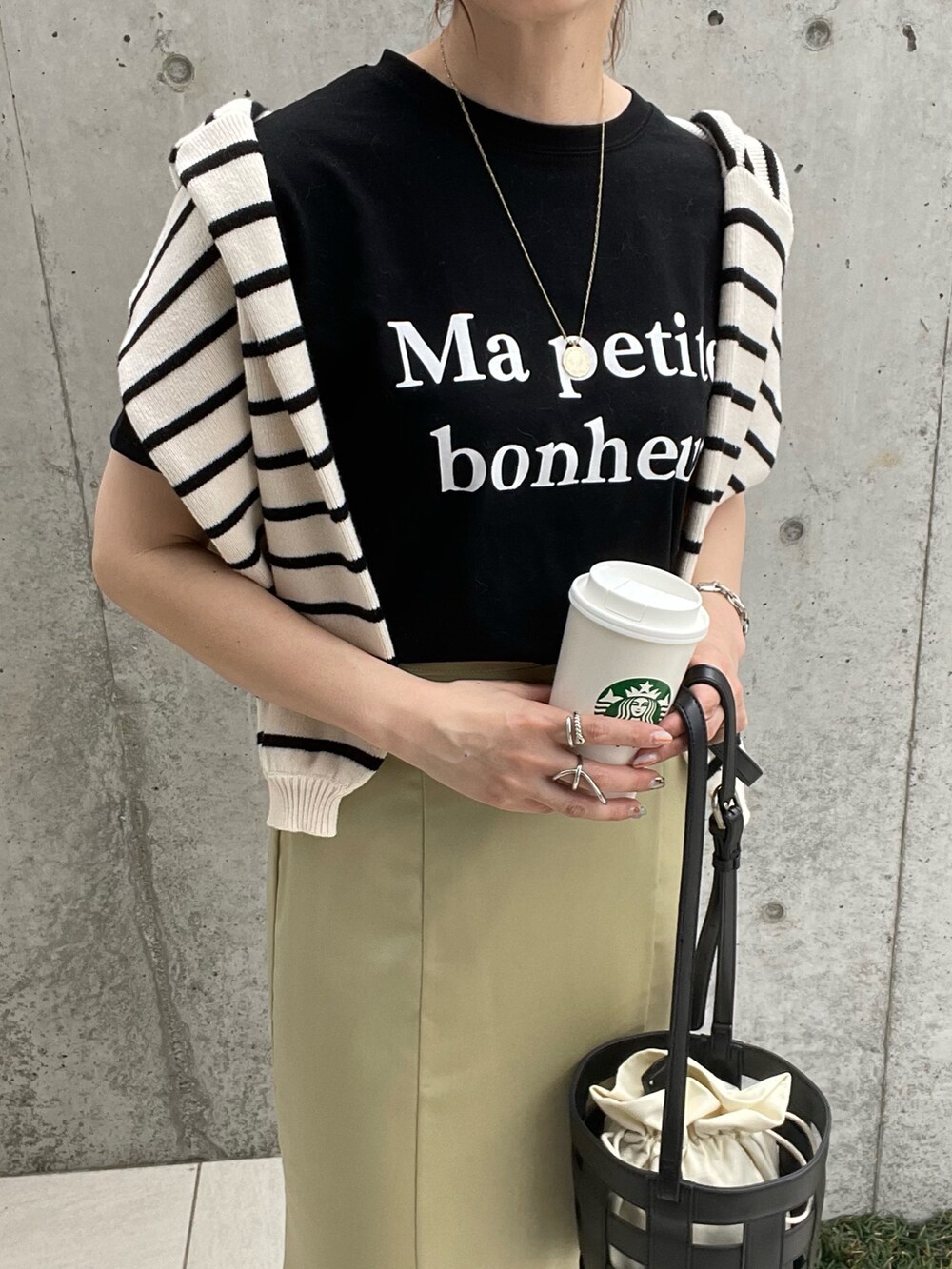 ブラック系のショルダーバッグ、イエロー系のスカート、ブラック系のスニーカーを着用したレディースの春コーディネートの3枚目の写真