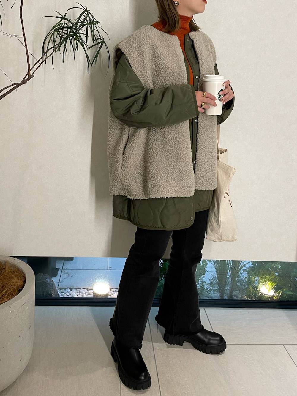 グリーン系のその他アウター、オレンジ系のニット/セーター、ブラック系のデニムパンツを着用したレディースの秋コーディネートの2枚目の写真