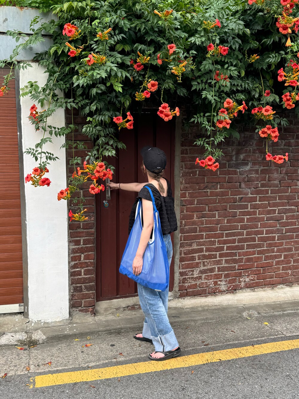 ブラック系のその他トップス、ブルー系のデニムパンツ、ブルー系のトートバッグを着用したレディースの夏コーディネートの3枚目の写真