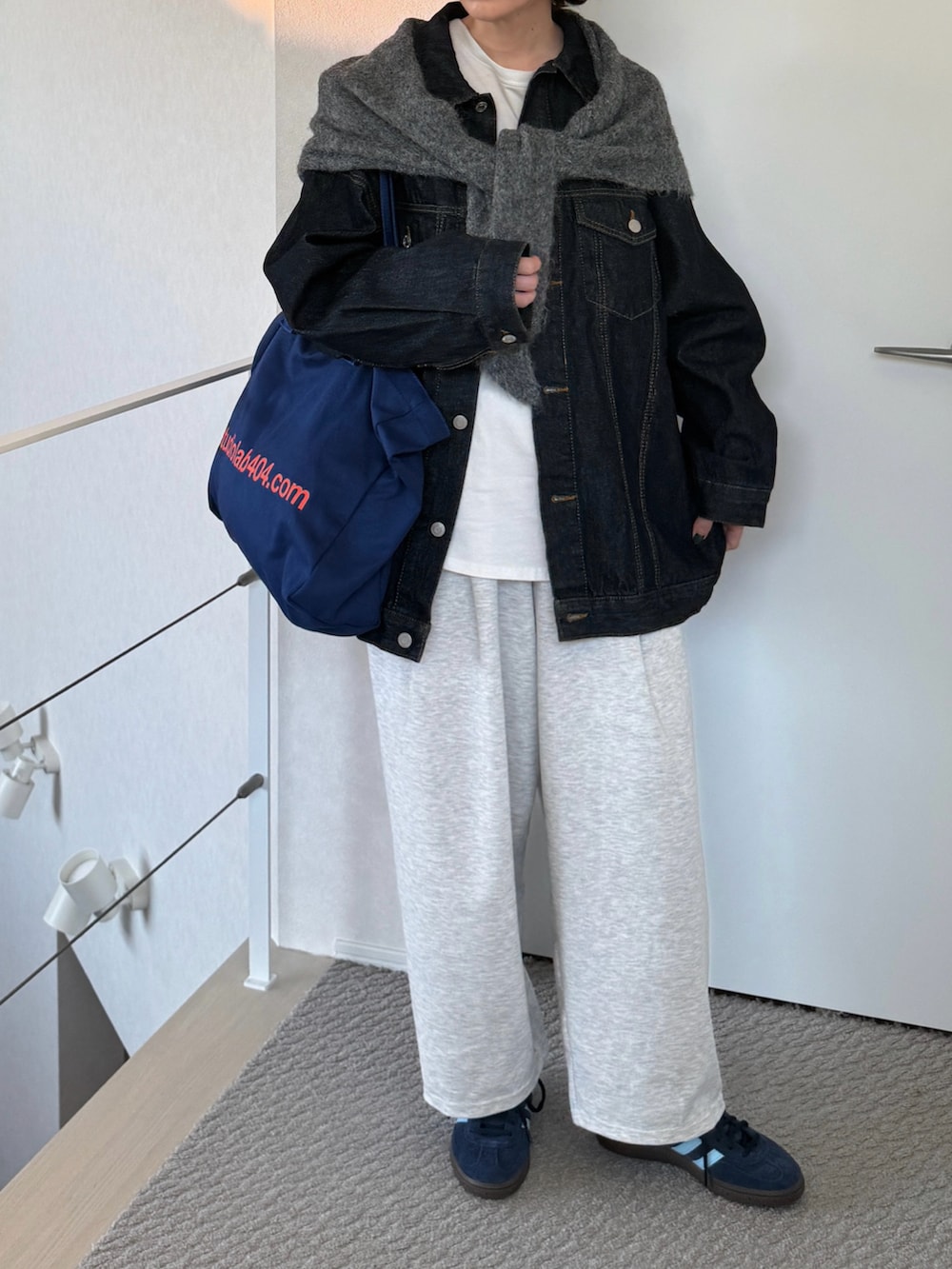 ブルー系のブルゾン、グレー系のデニムパンツ、ブルー系のスニーカーを着用したレディースの秋コーディネートの2枚目の写真