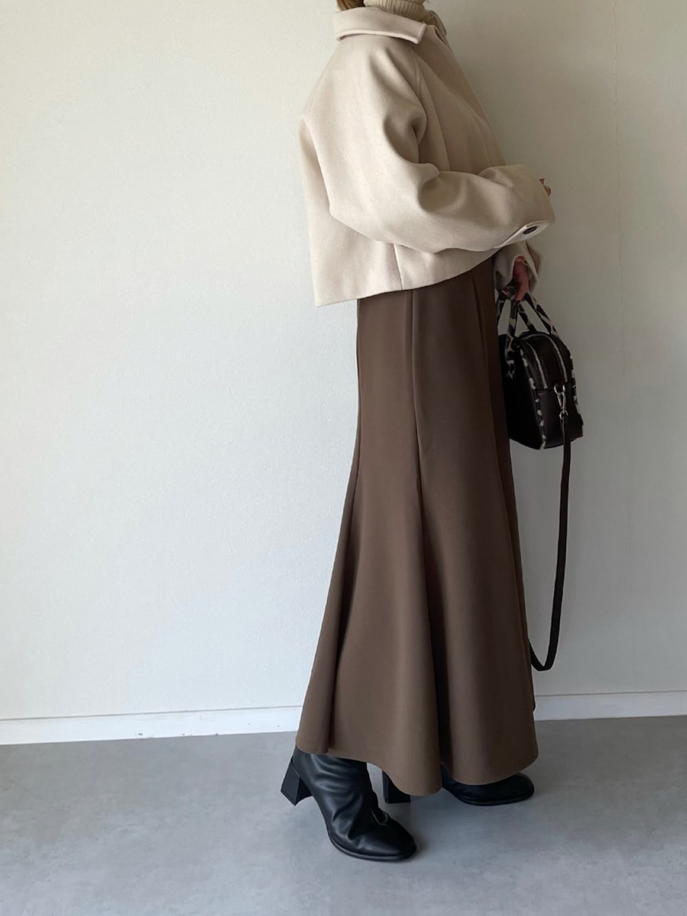 ホワイト系のその他アウター、ブラウン系のスカート、ブラック系のブーツを着用したレディースの秋コーディネートの3枚目の写真