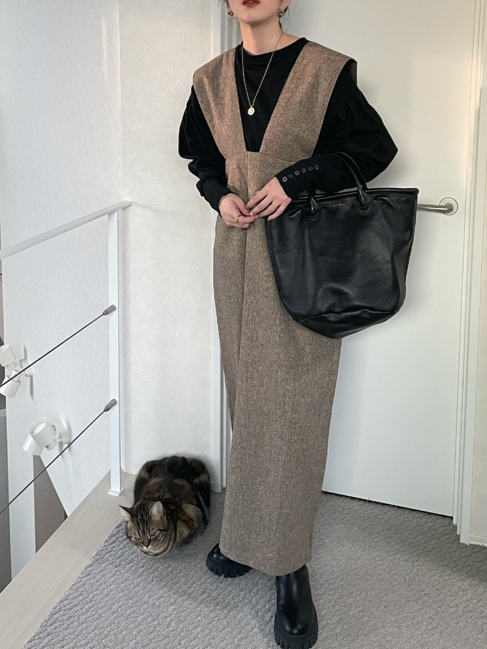 ブラウン系のジャンパースカート、ブラック系のTシャツ/カットソー、ブラック系のブーツを着用したレディースの冬コーディネートの3枚目の写真