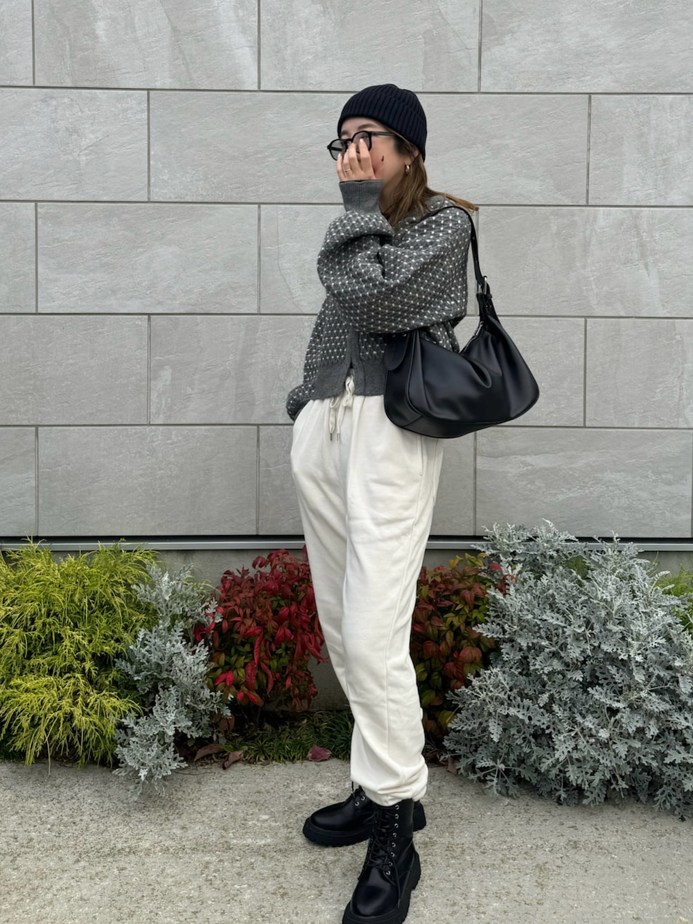 グレー系のニット/セーター、ブラック系のハンドバッグ、ブラック系のブーツを着用したレディースの秋コーディネートの2枚目の写真