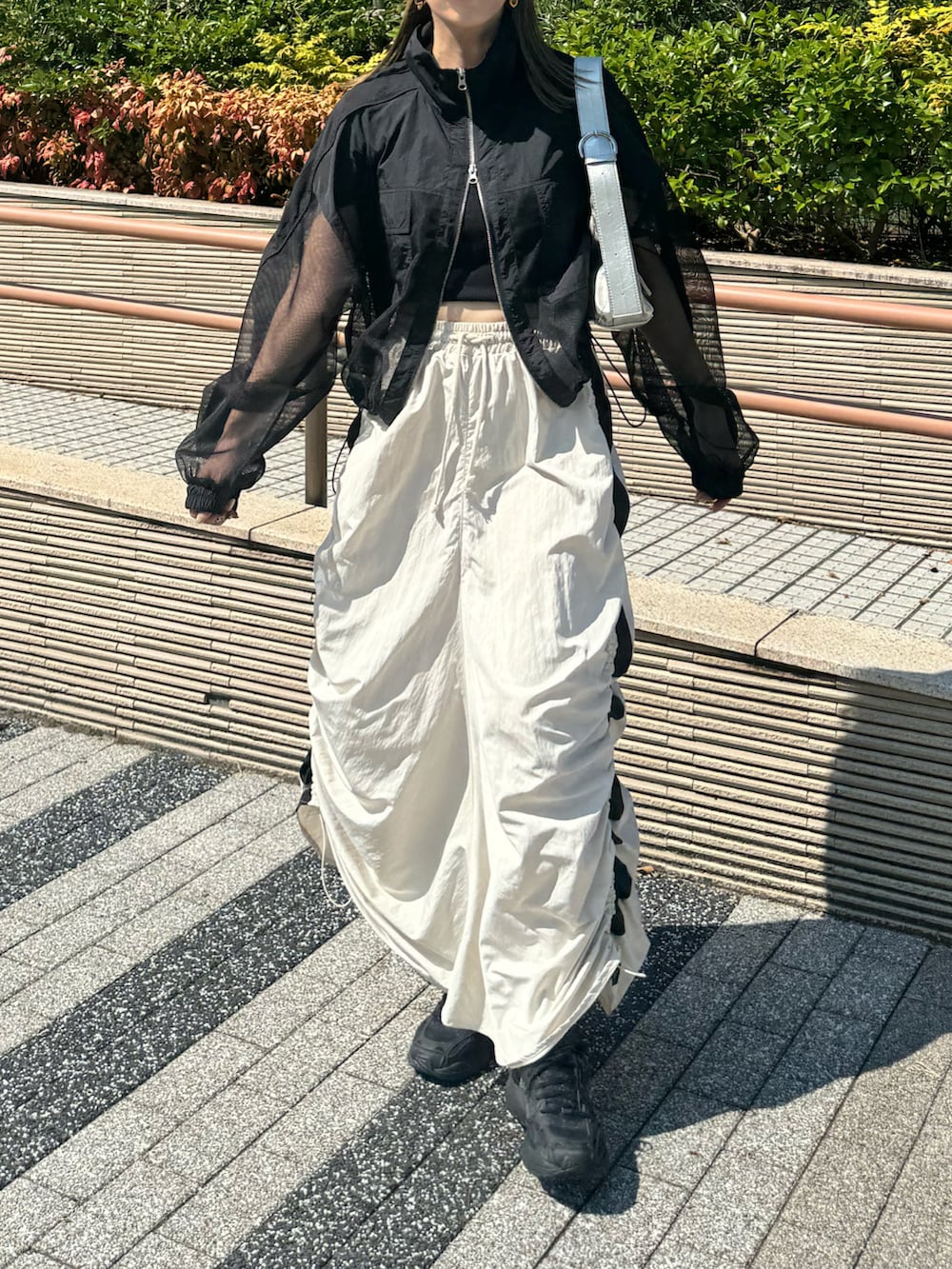 ホワイト系のスカート、ブラック系のブルゾン、シルバー系のショルダーバッグを着用したレディースの秋コーディネートの4枚目の写真