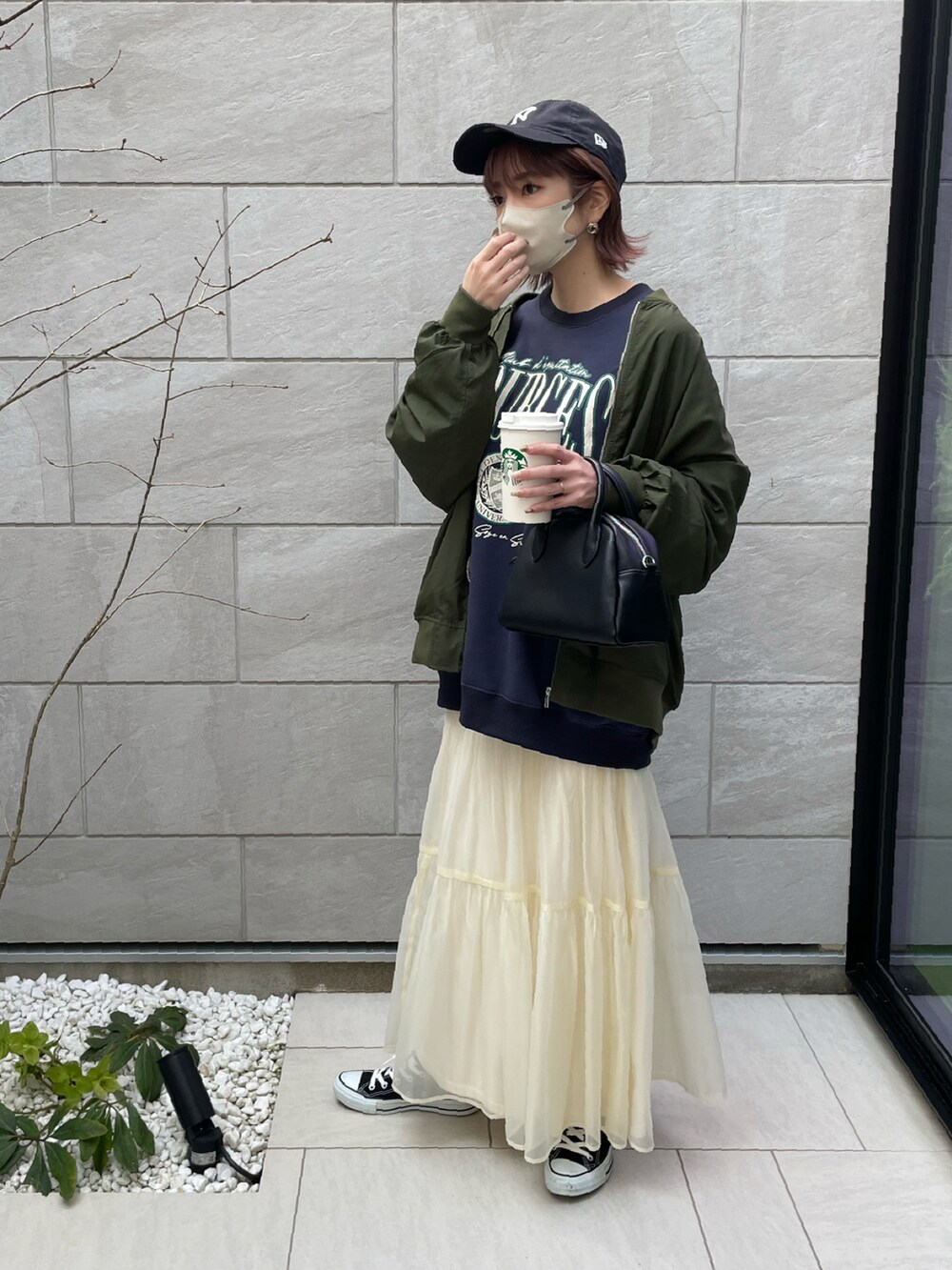 グリーン系のブルゾン、ホワイト系のスカート、ブルー系のスウェットを着用したレディースの春コーディネートの2枚目の写真