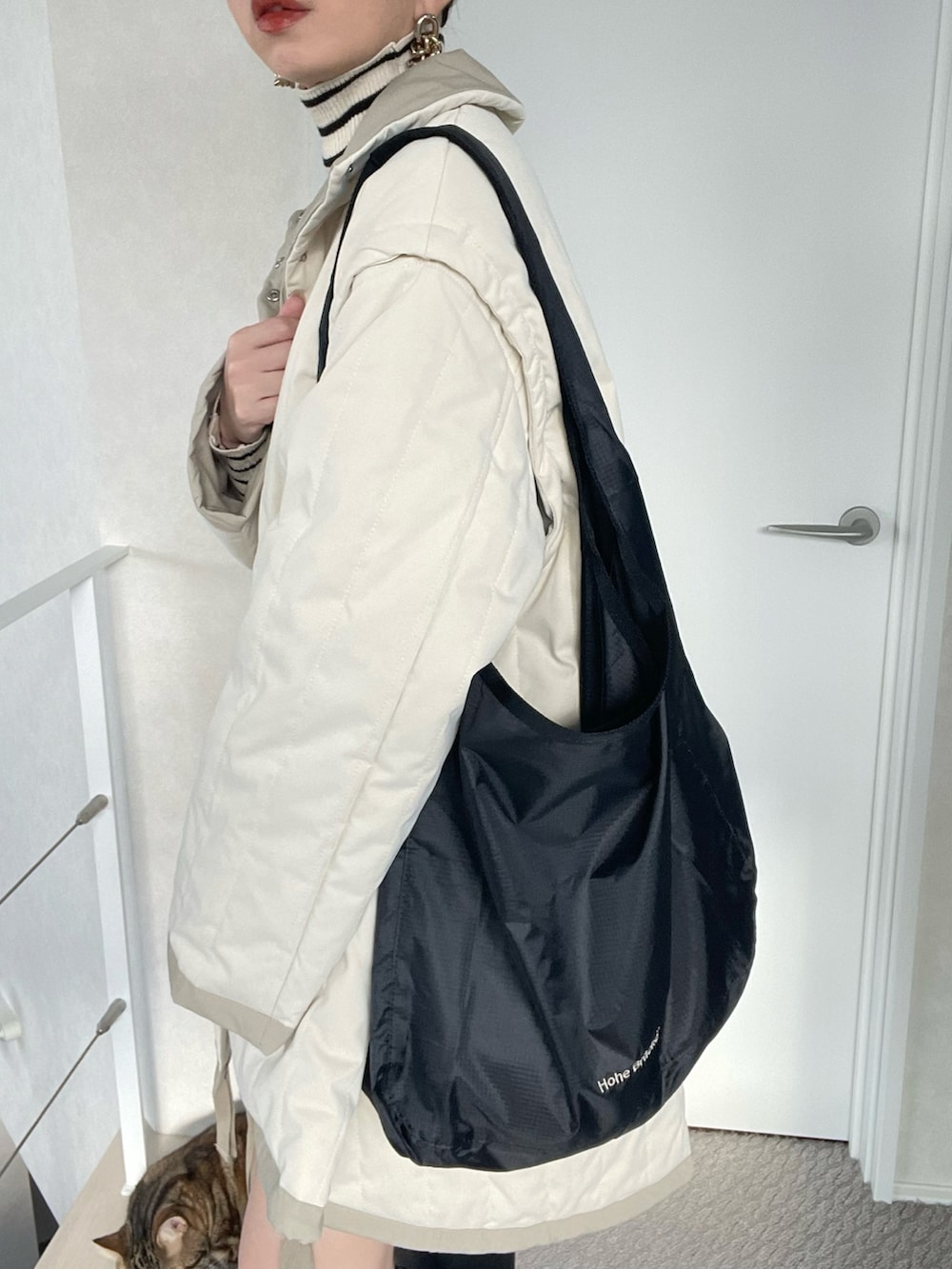 ブラック系のショルダーバッグ、ブラック系のニット/セーター、ホワイト系のダウンジャケット/コートを着用したレディースの冬コーディネートの5枚目の写真