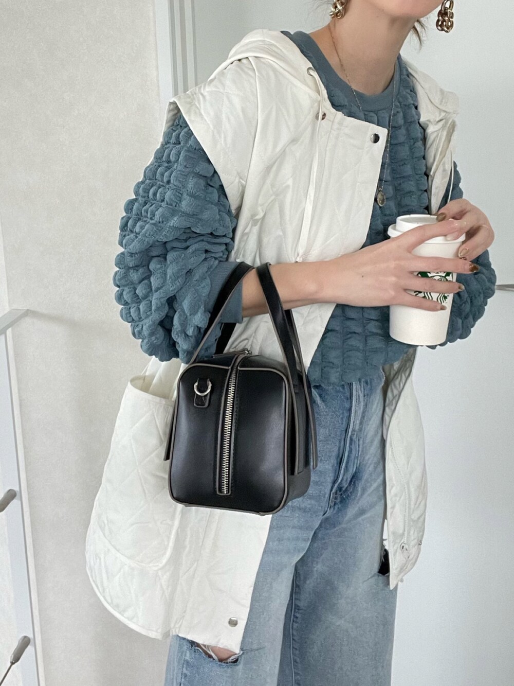 ブルー系のTシャツ/カットソー、ホワイト系のベスト、ブラック系のボストンバッグを着用したレディースの冬コーディネートの4枚目の写真