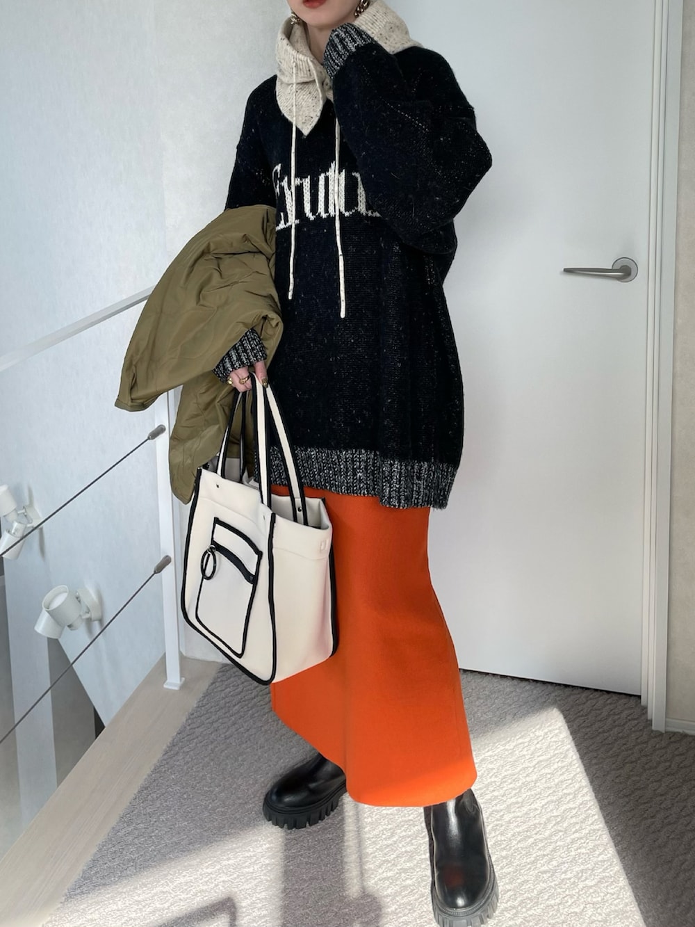 グリーン系のノーカラージャケット、ブラック系のニット/セーター、ホワイト系のトートバッグを着用したレディースの冬コーディネートの2枚目の写真