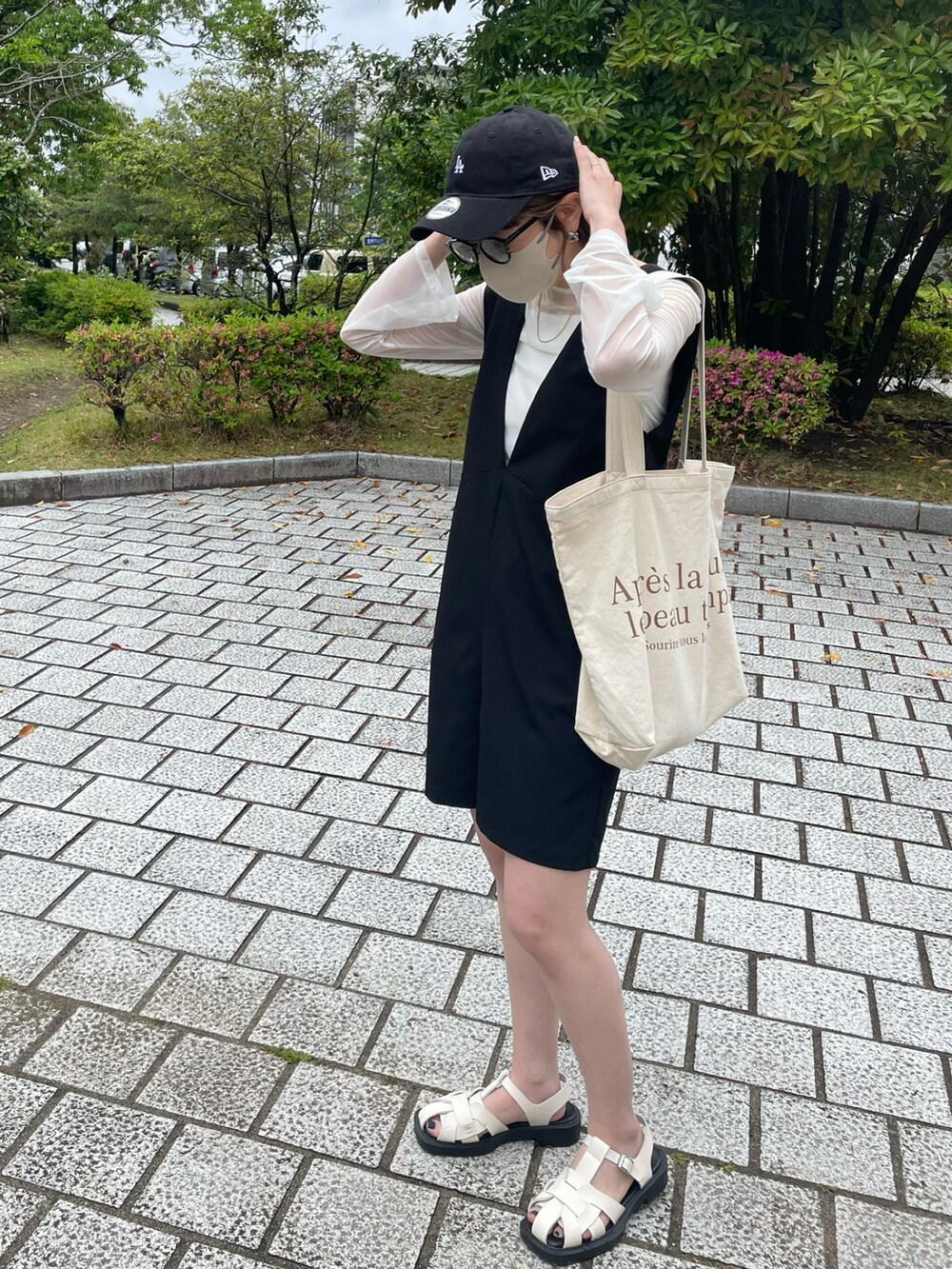 ブラック系のサロペット/オーバーオール、ホワイト系のTシャツ/カットソー、ホワイト系のサンダルを着用したレディースの春コーディネートの2枚目の写真