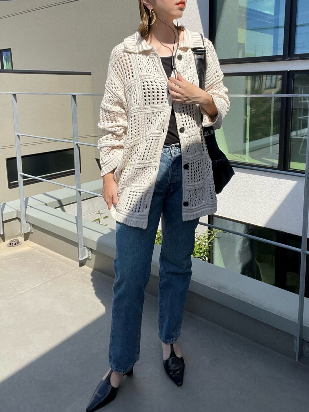 ブルー系のデニムパンツ、ホワイト系のカーディガン/ボレロ、ブラック系のパンプスを着用したレディースの秋コーディネートの3枚目の写真