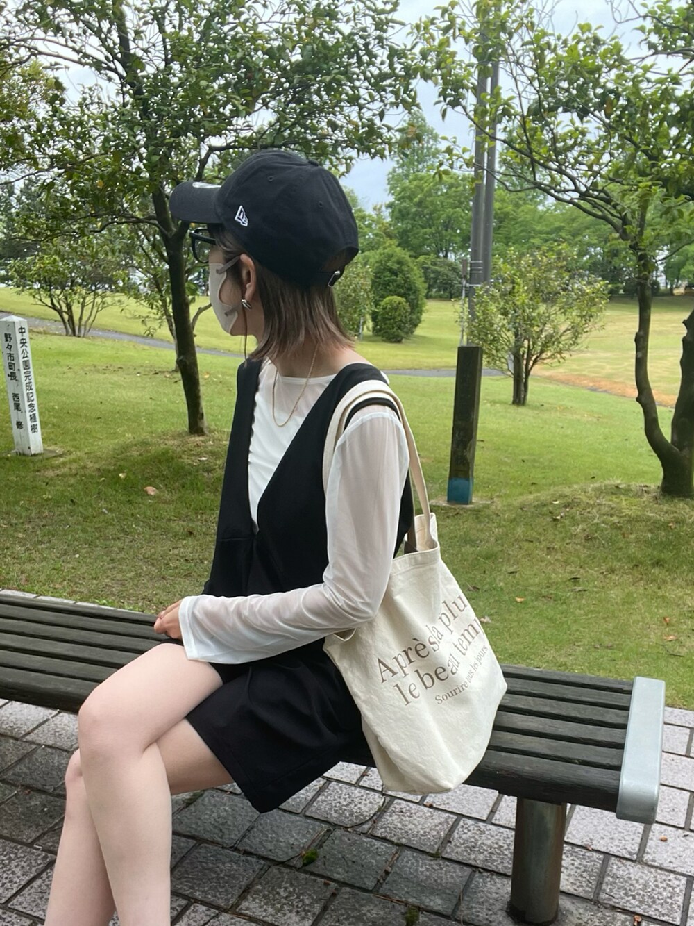 ブラック系のサロペット/オーバーオール、ホワイト系のTシャツ/カットソー、ホワイト系のサンダルを着用したレディースの春コーディネートの4枚目の写真