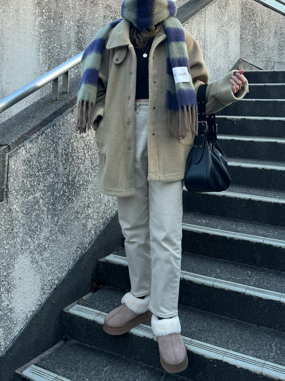 ブラック系のハンドバッグ、グリーン系のその他アウター、グリーン系のマフラーを着用したレディースの冬コーディネートの3枚目の写真