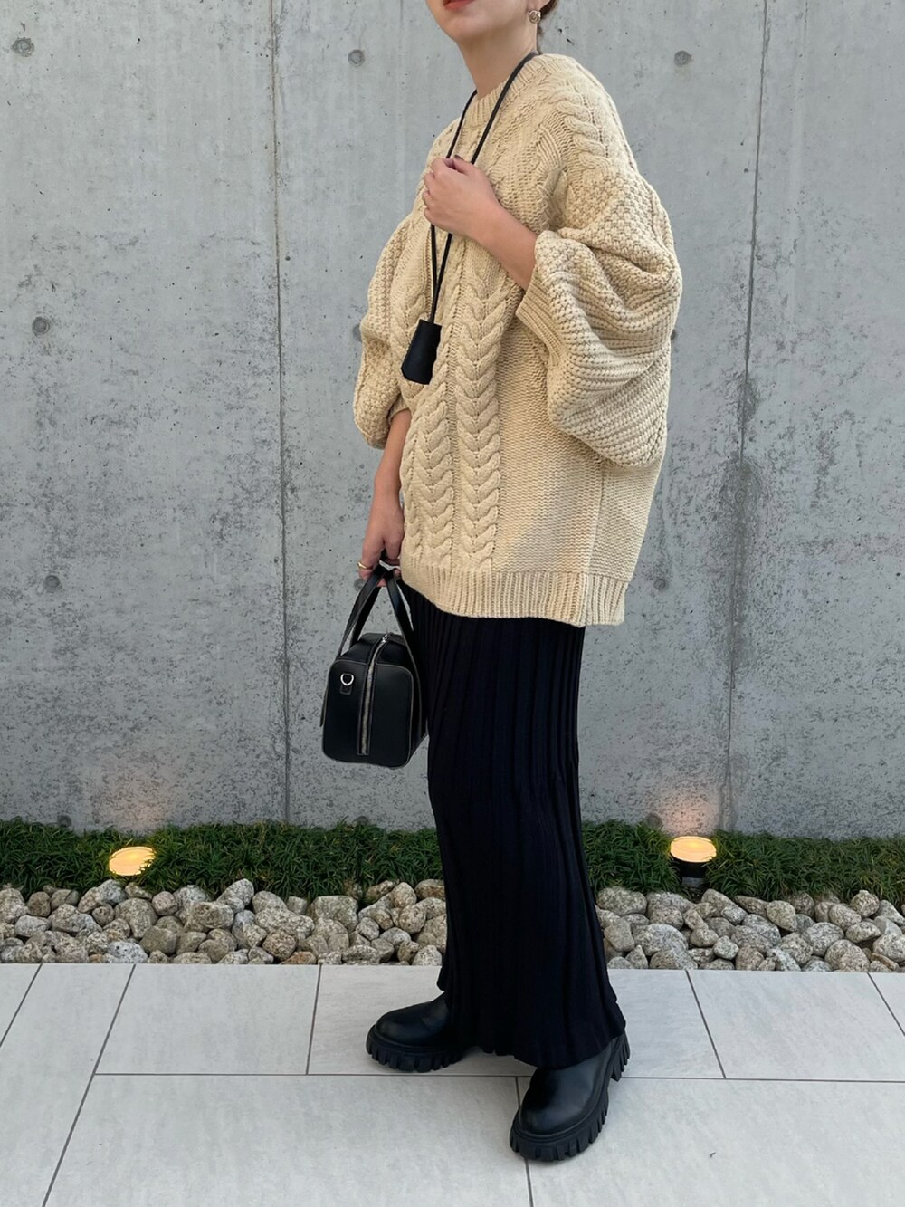 ホワイト系のニット/セーター、ブラック系のスカート、ブラック系のブーツを着用したレディースの秋コーディネートの2枚目の写真