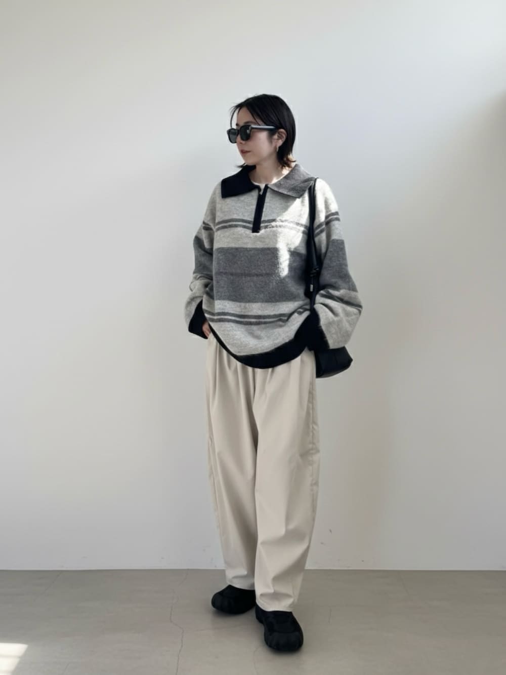 グレー系のニット/セーター、ホワイト系のチノパンツ、ブラック系のスニーカーを着用したレディースの冬コーディネートの3枚目の写真