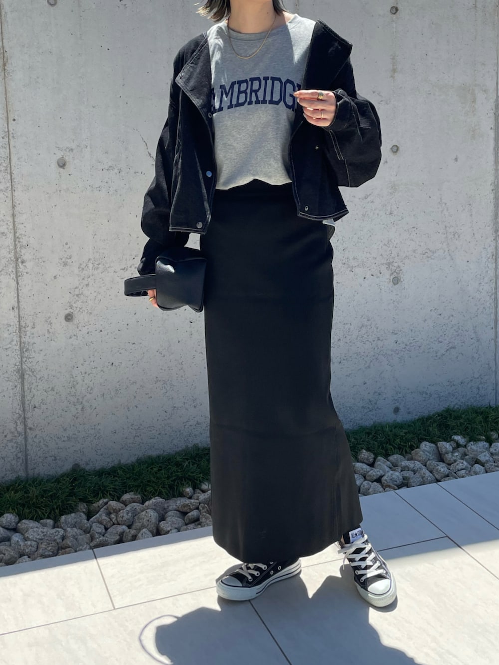 グレー系のTシャツ/カットソー、ブラック系のスカート、ブラック系のデニムジャケットを着用したレディースの秋コーディネートの2枚目の写真