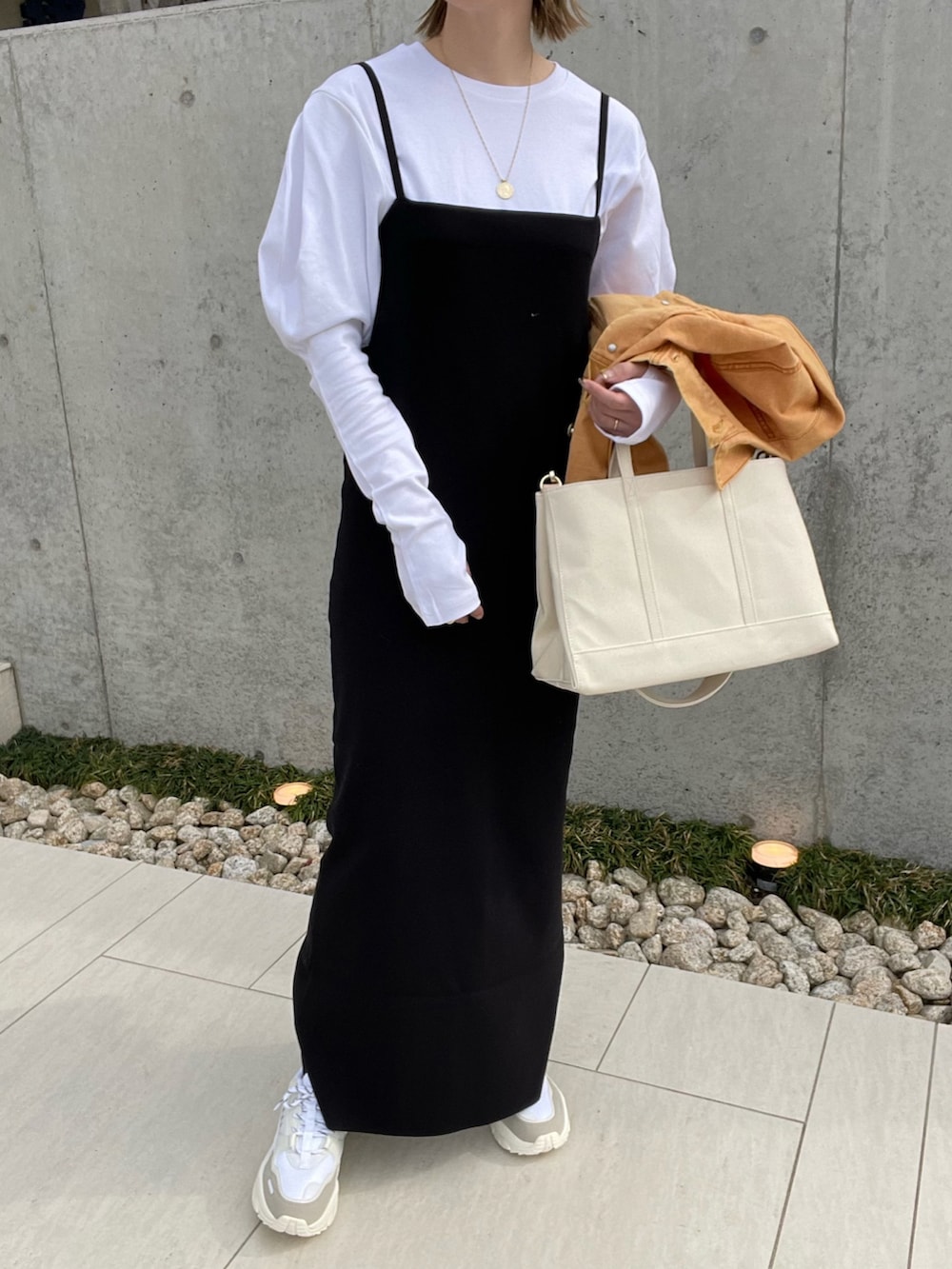 ホワイト系のトートバッグ、オレンジ系のデニムジャケット、ブラック系のワンピースを着用したレディースの春コーディネートの3枚目の写真