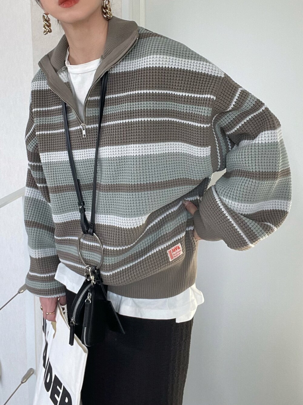 ブラック系のスカート、ブルー系のニット/セーター、ブラック系のショルダーバッグを着用したレディースの冬コーディネートの5枚目の写真