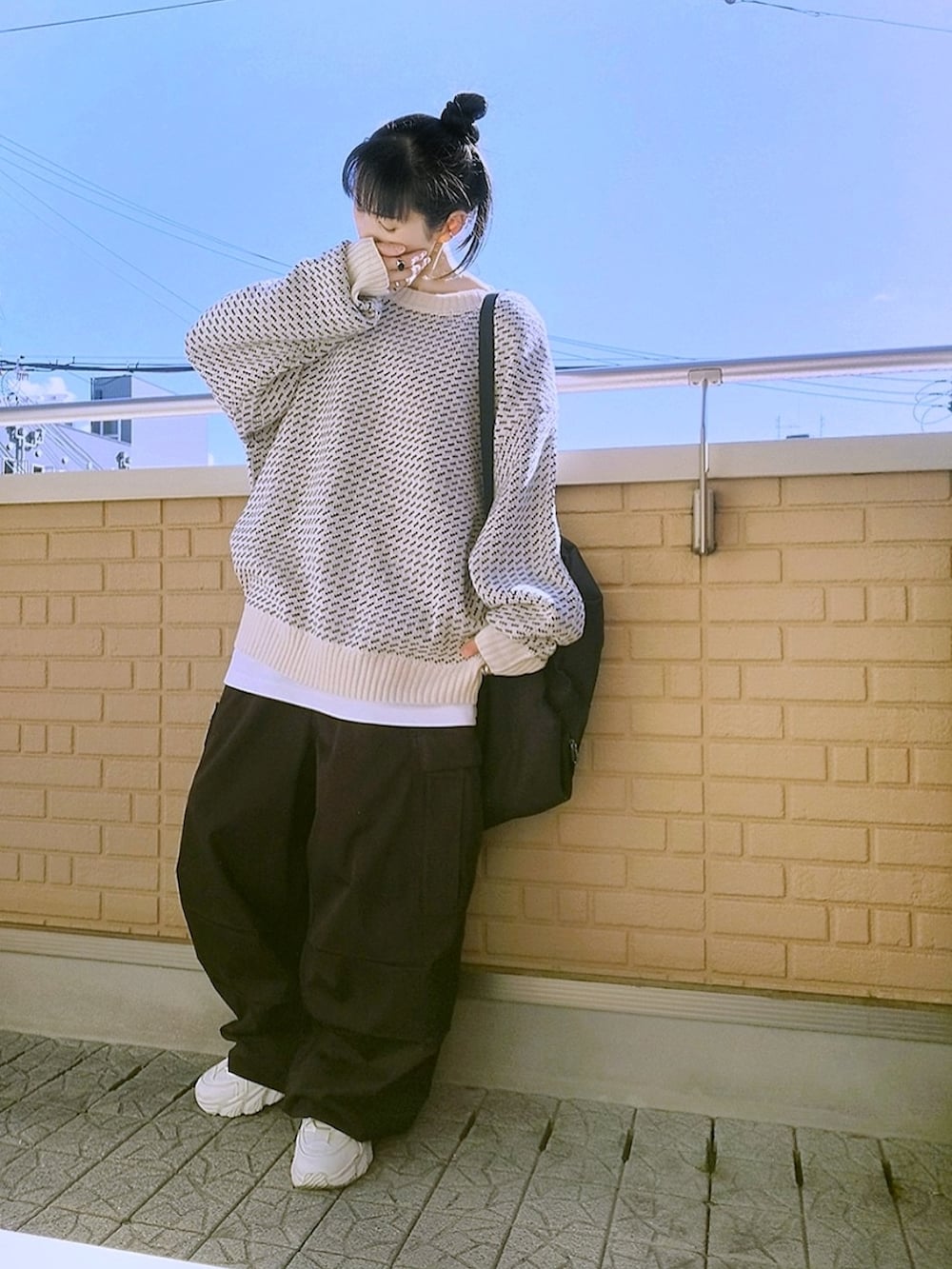 ブラック系のカーゴパンツ、ホワイト系のスニーカー、ホワイト系のニット/セーターを着用したレディースの秋コーディネートの2枚目の写真
