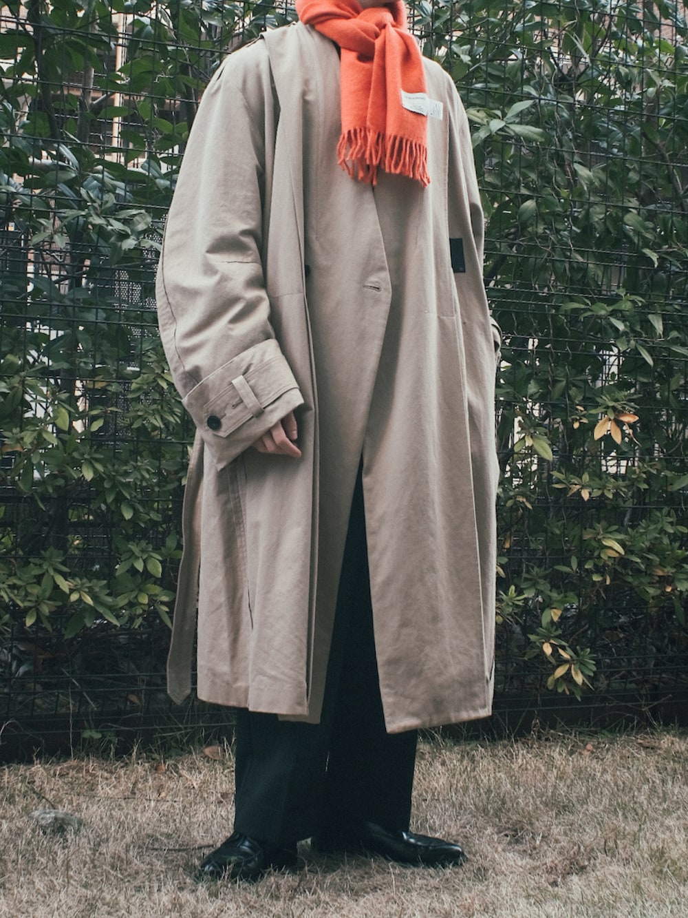 ベージュ系のトレンチコート、ブラック系のスラックス、ブラック系のドレスシューズを着用したメンズの冬コーディネートの2枚目の写真