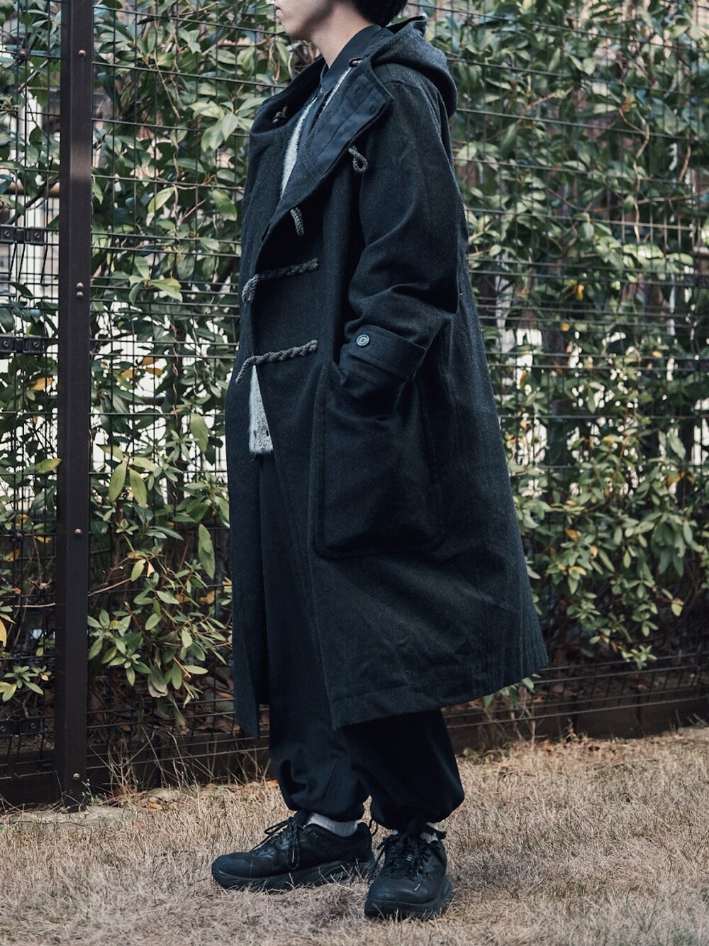 ブラック系のダッフルコート、ブラック系のカーディガン/ボレロ、ブラック系のシャツ/ブラウスを着用したメンズの冬コーディネートの2枚目の写真