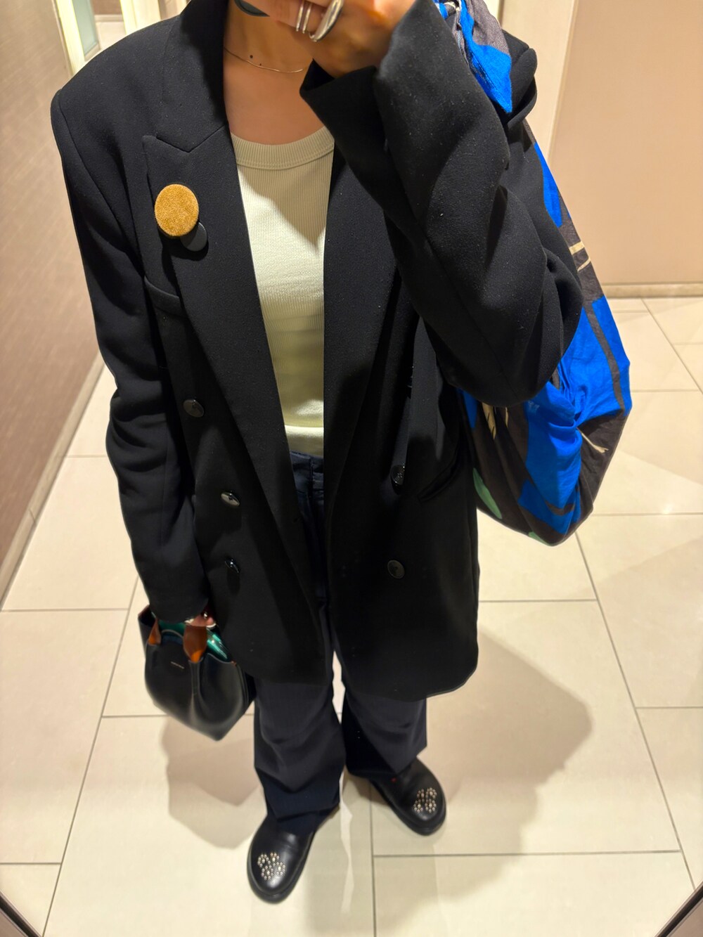 ブルー系のスラックス、ブラック系のハンドバッグを着用したレディースの春コーディネートの2枚目の写真